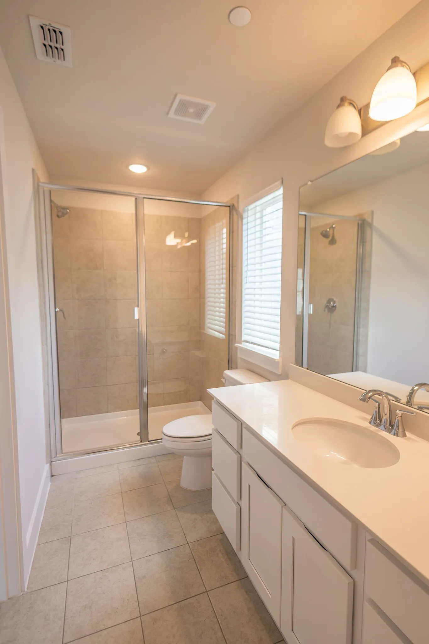 Glass-enclosed shower with a built-in shelf, neutral-toned tile surround, and a white shower pan
