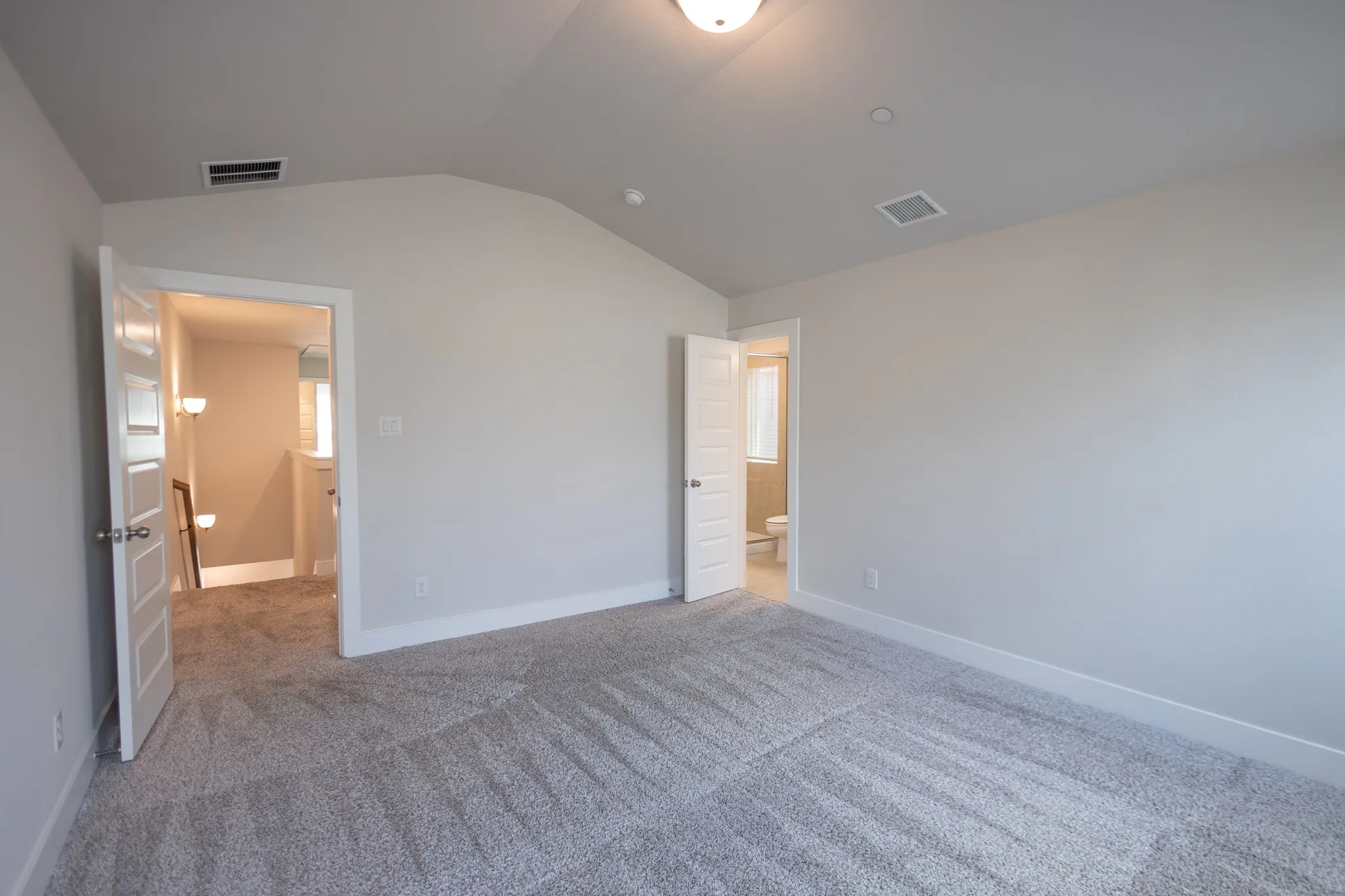 Room featuring vaulted ceilings, carpeted flooring, two windows with blinds, a ceiling-mounted light fixture, and white baseboards