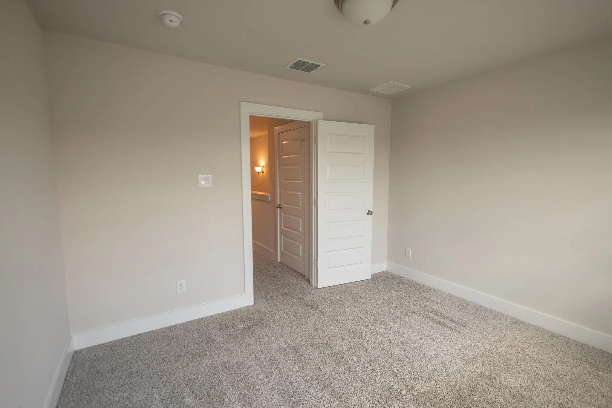 Bedroom with carpeted flooring, three windows with blinds, a ceiling-mounted light fixture, and white baseboards