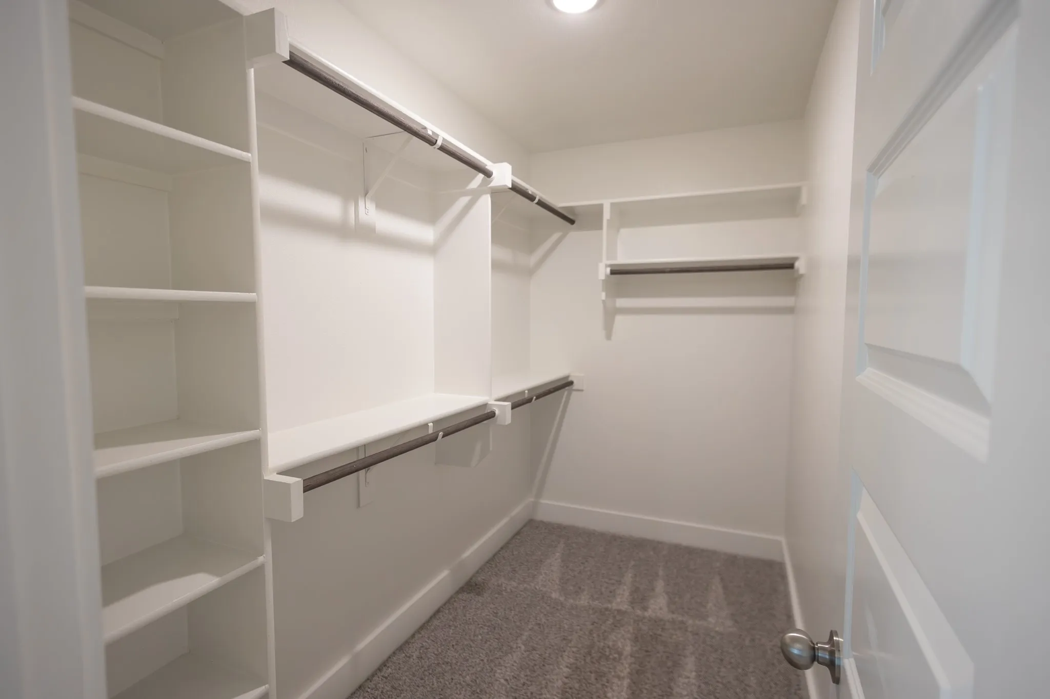 Walk-in closet featuring built-in shelving, multiple hanging rods, recessed ceiling lighting, and textured carpeting