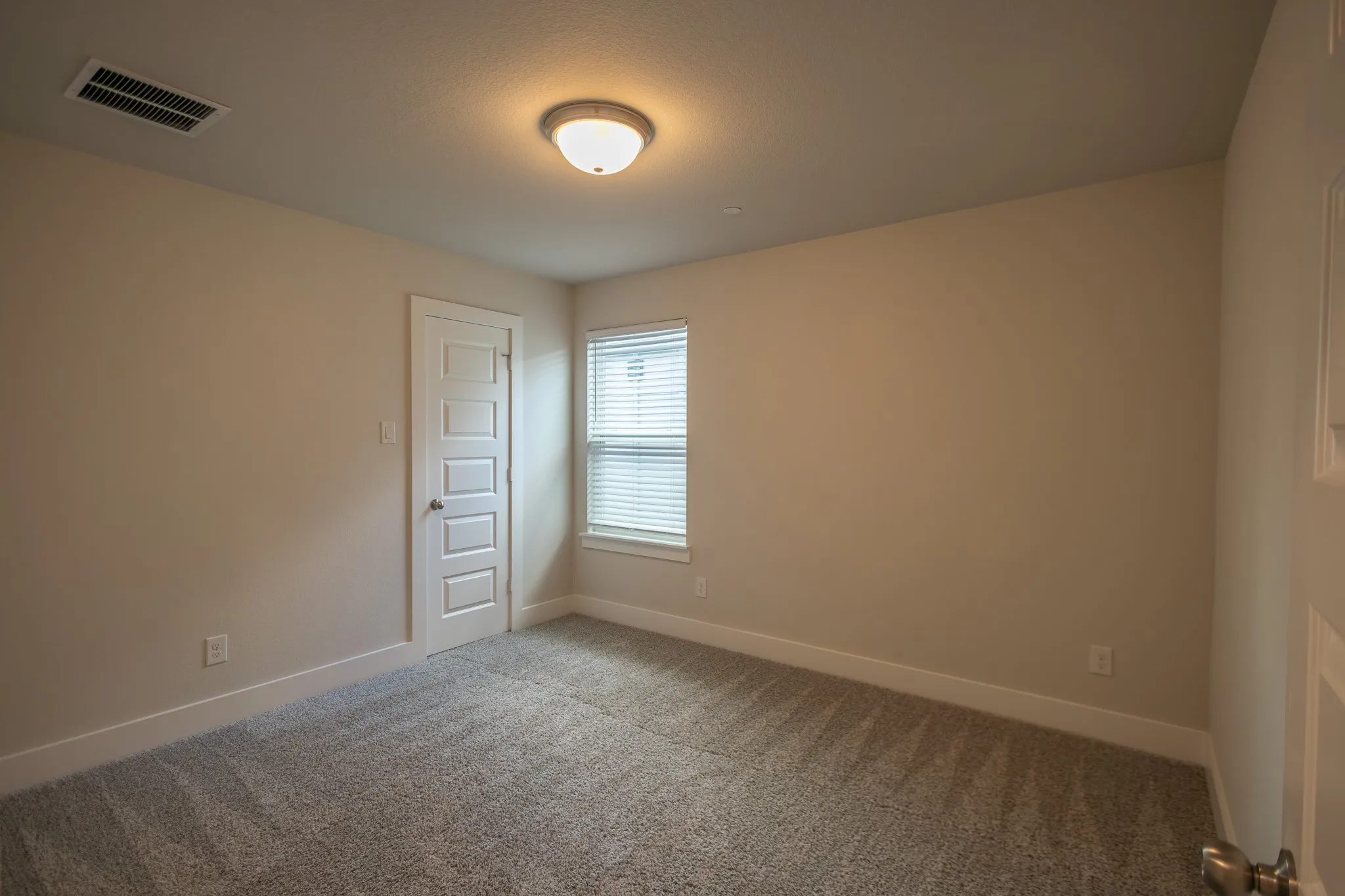Carpeted room featuring a white paneled door, a single window, recessed lighting, and neutral wall paint