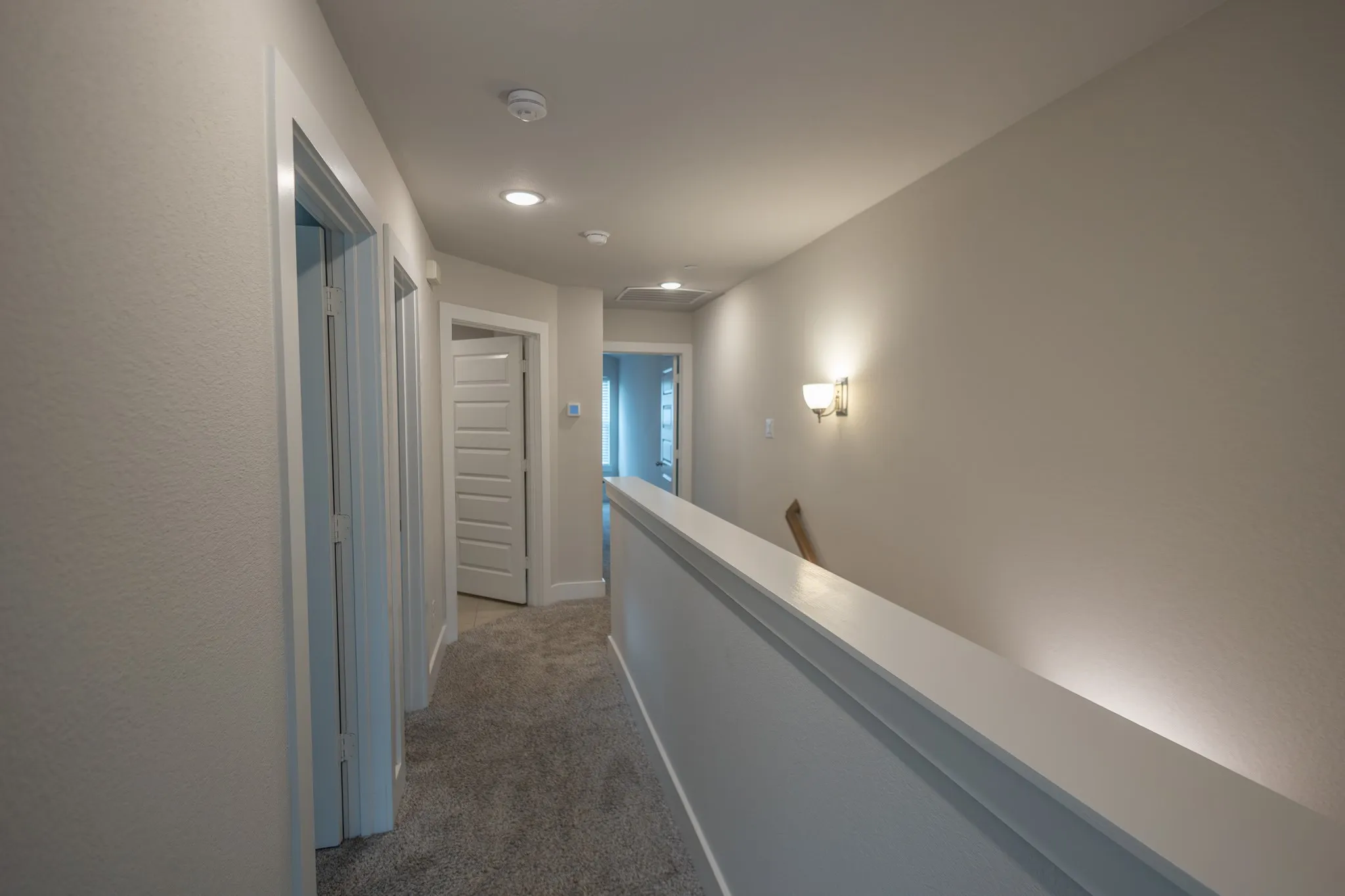 Second-story hallway featuring gray flecked carpet flooring and white baseboards