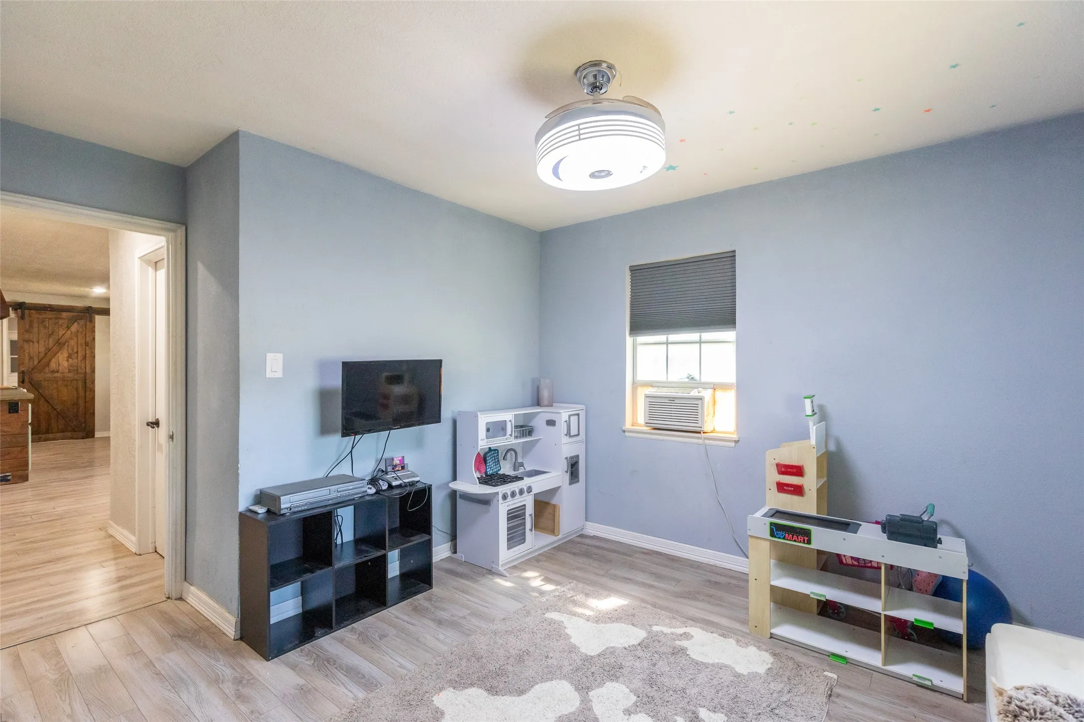 Room featuring light blue walls, wood-finish flooring, and a ceiling-mounted light fixture