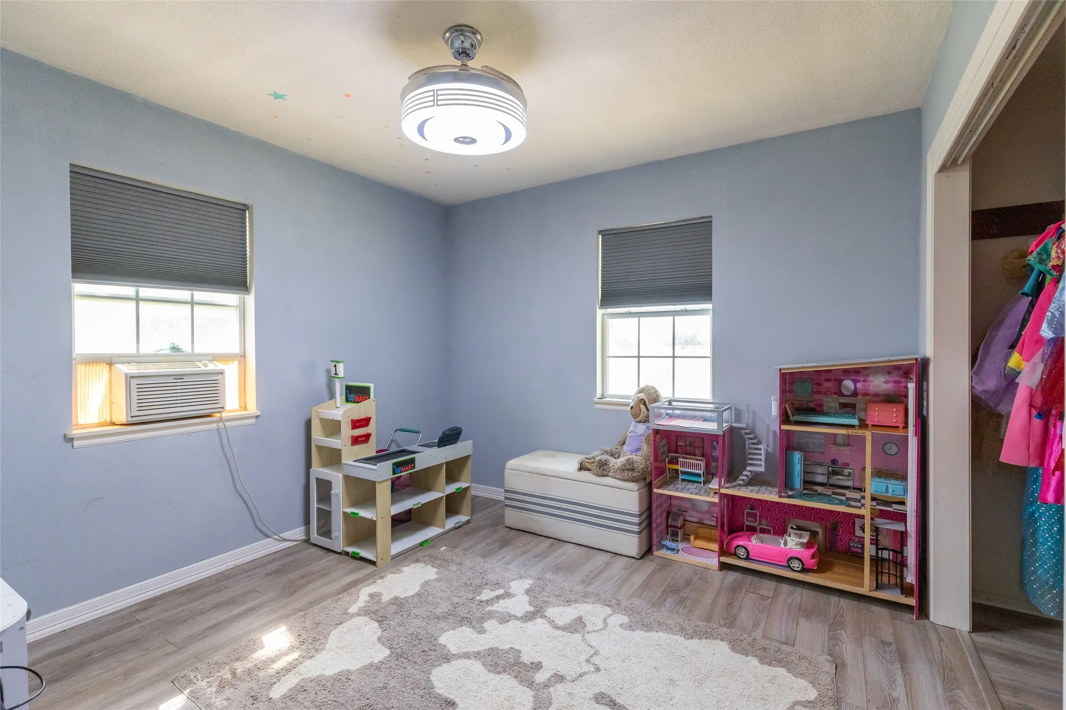 Room featuring wood-finish flooring, two window openings with blinds, a ceiling-mounted light fixture, and a closet opening