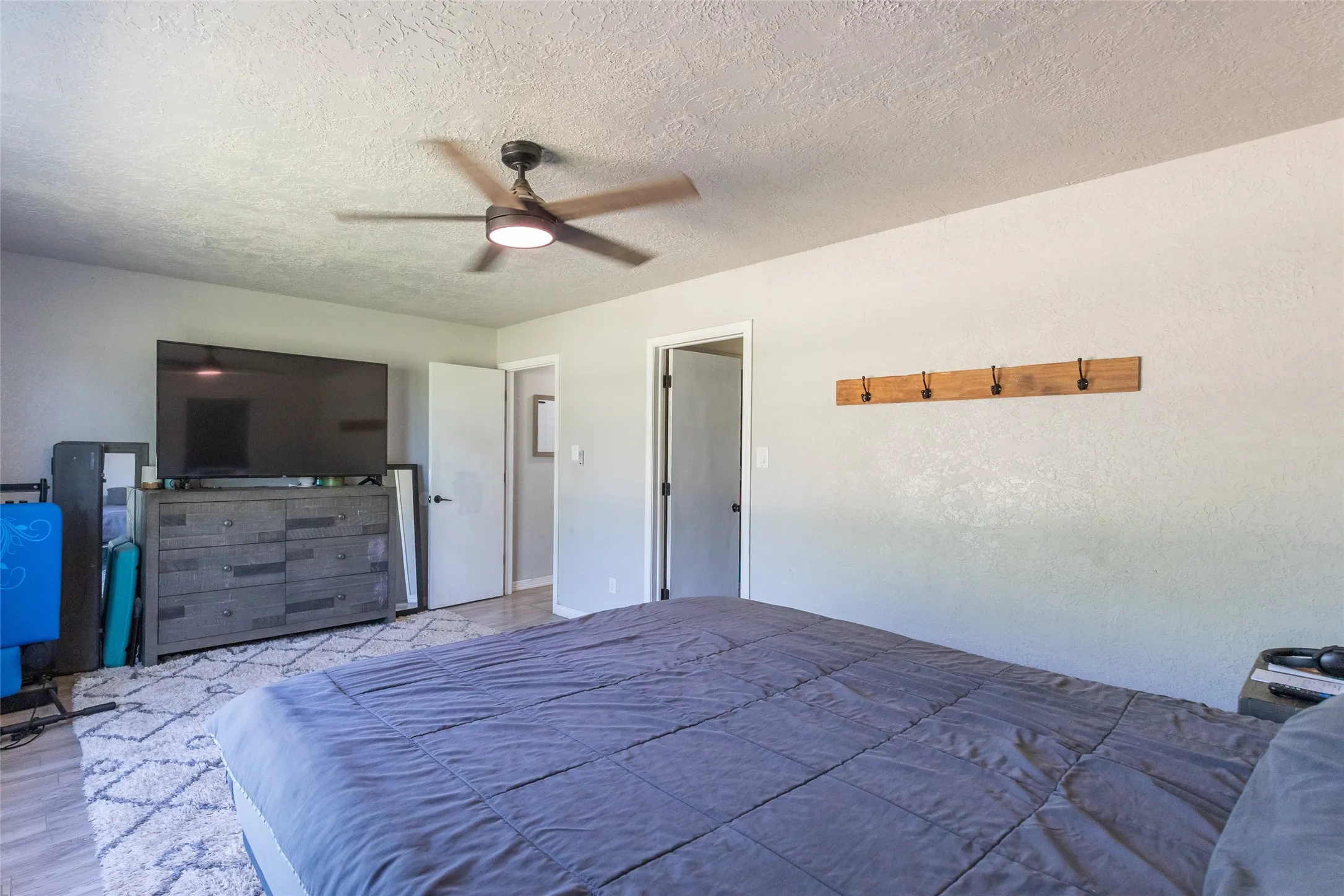 Interior room featuring a ceiling fan with integrated lighting, wood-finish flooring, and light-toned walls