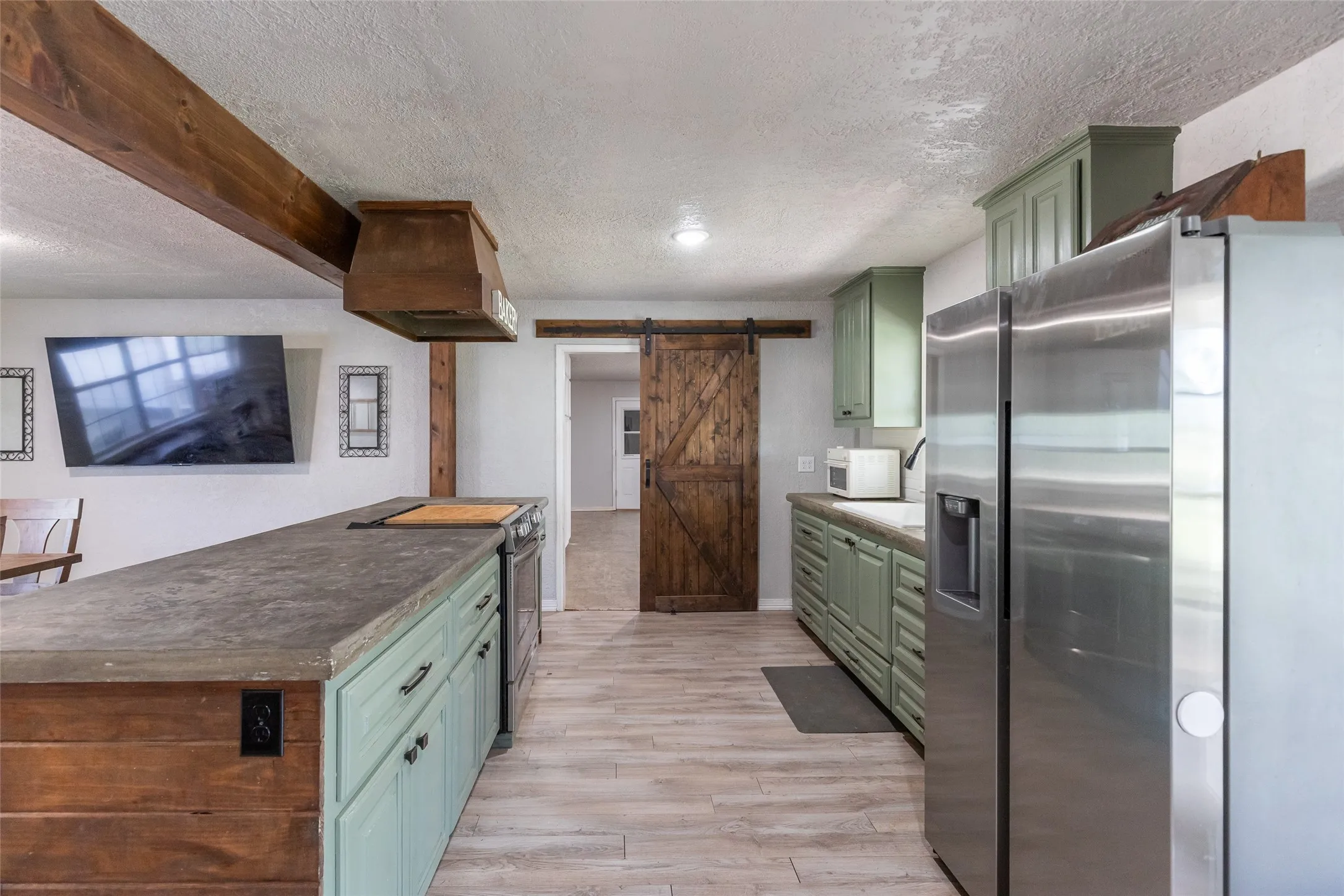 Kitchen featuring a large island with a concrete countertop, integrated cooktop, and wood-paneling detail