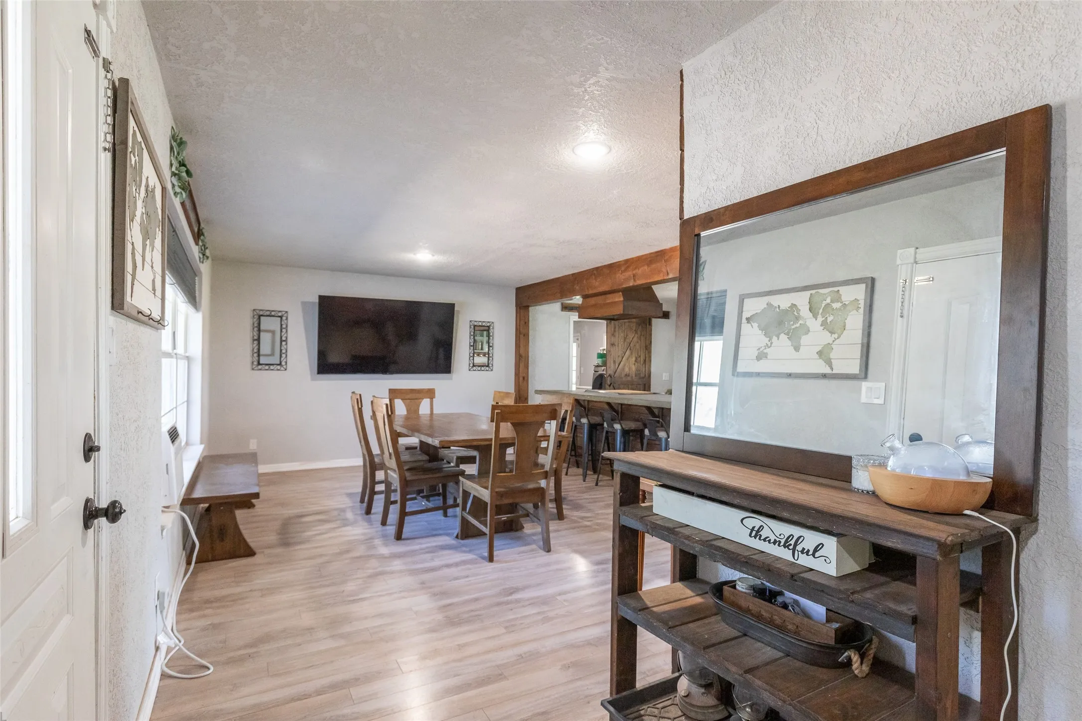 Open concept living area featuring wood-finish flooring, recessed lighting, and a prominent wood beam structural detail