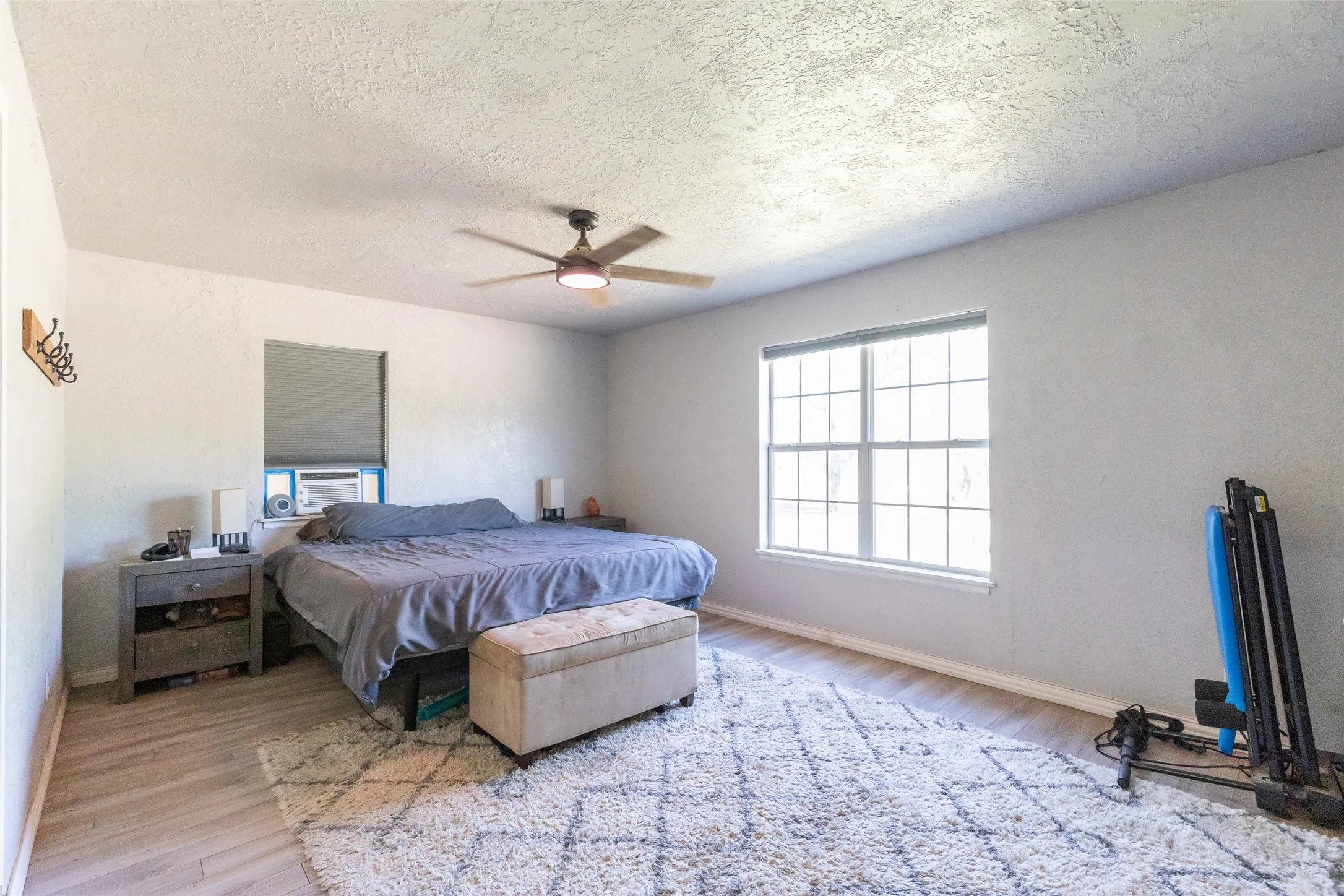 Spacious room featuring wood-finish flooring, a multi-pane window, and a ceiling fan with integrated lighting