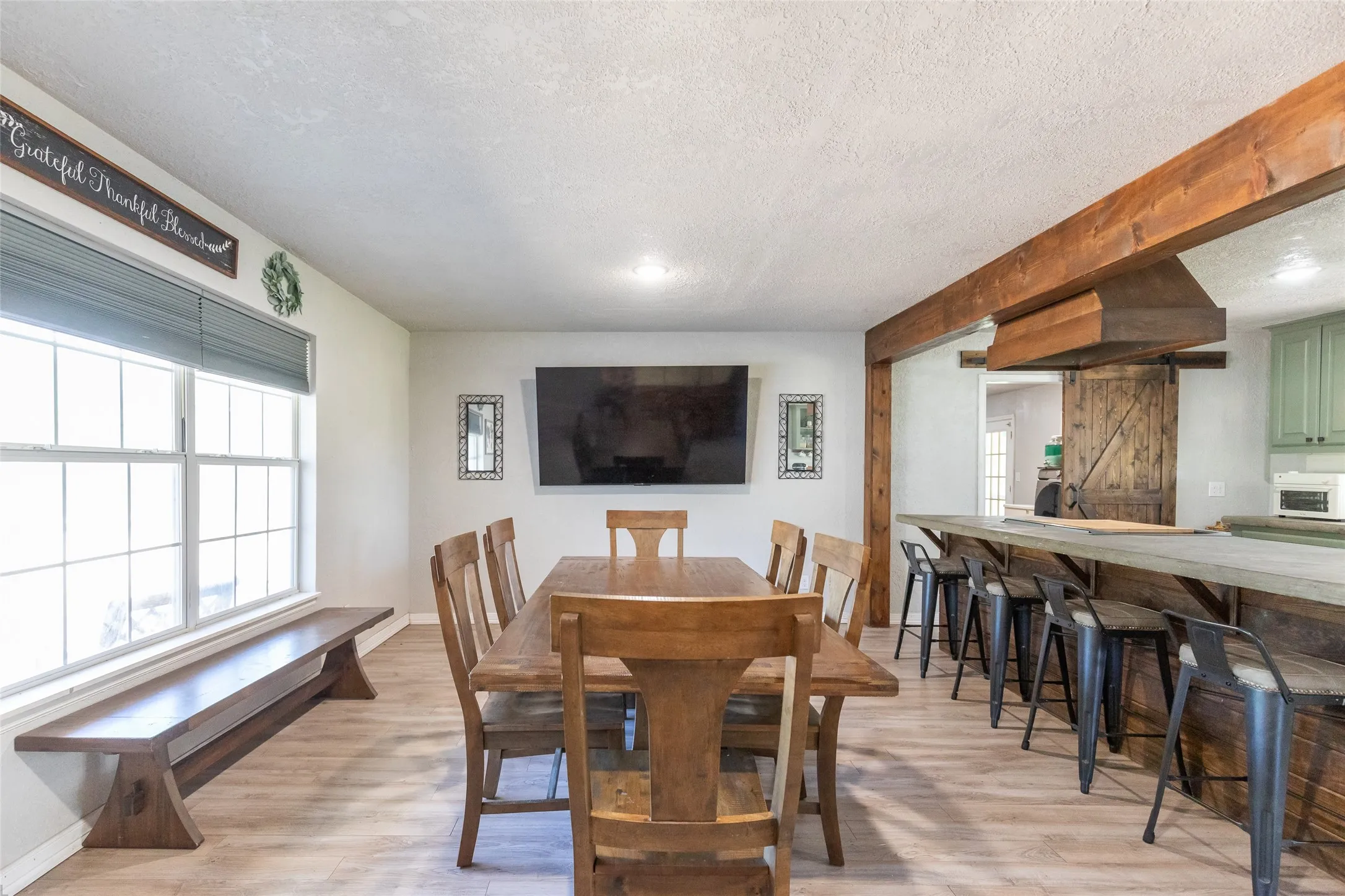 Dining area featuring wood-finish flooring, a built-in window bench, and an entertainment wall