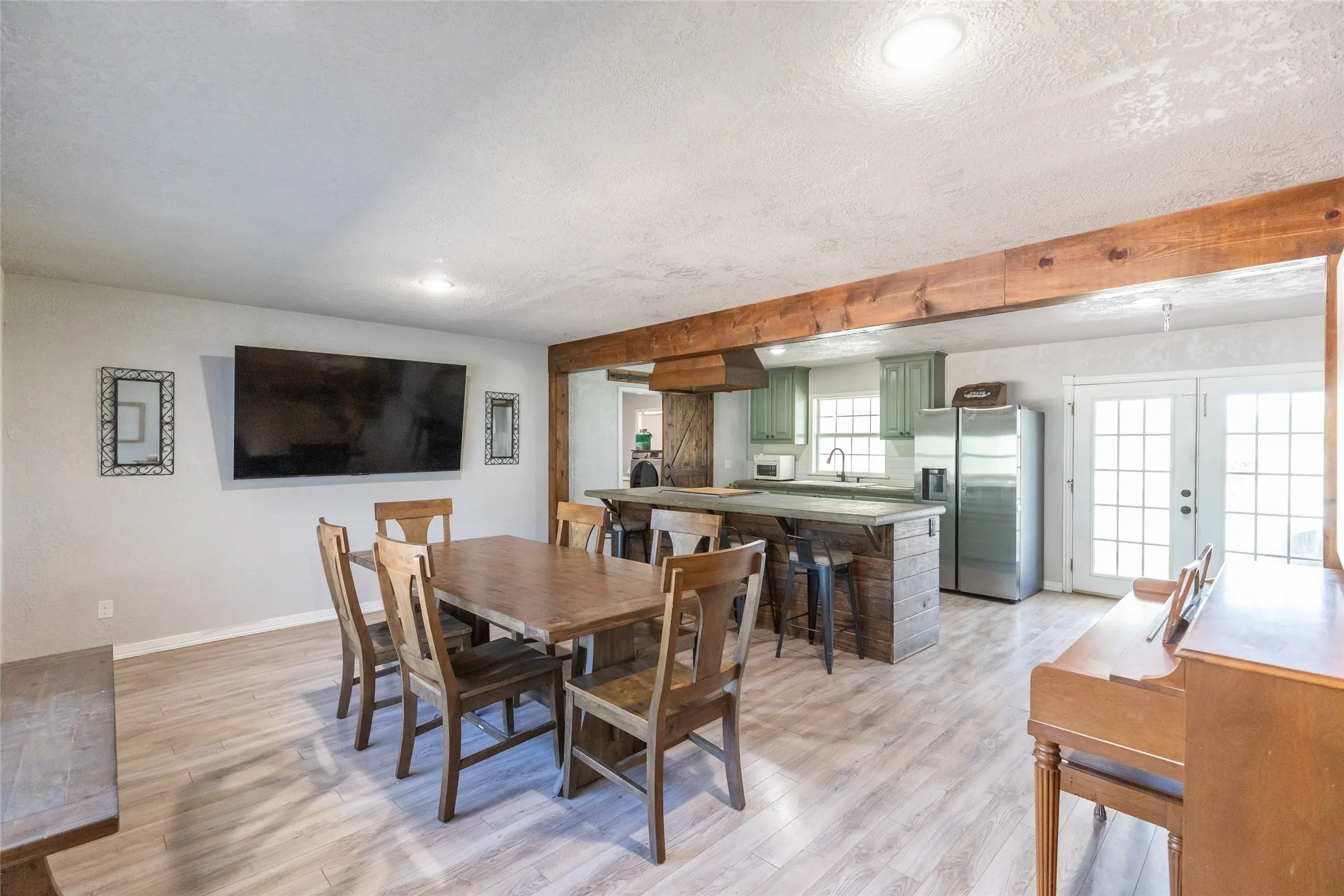 Open concept living space featuring wood-finish flooring and a substantial exposed wood beam