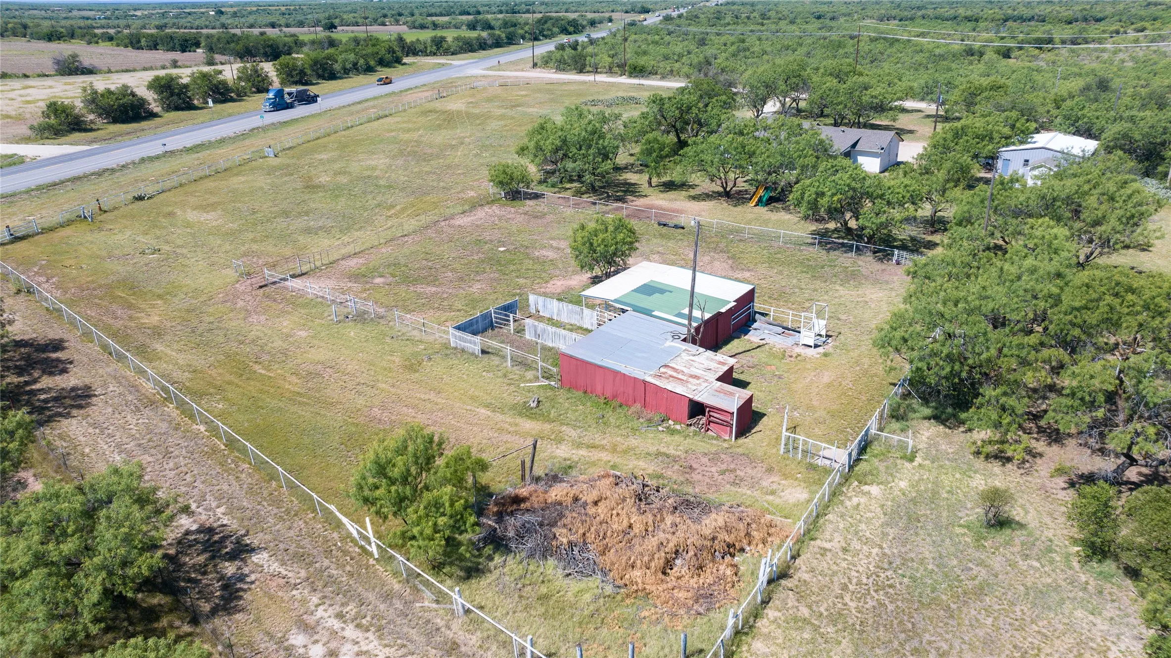 Expansive property featuring a red barn, a secondary outbuilding with a green roof, and multiple fenced areas