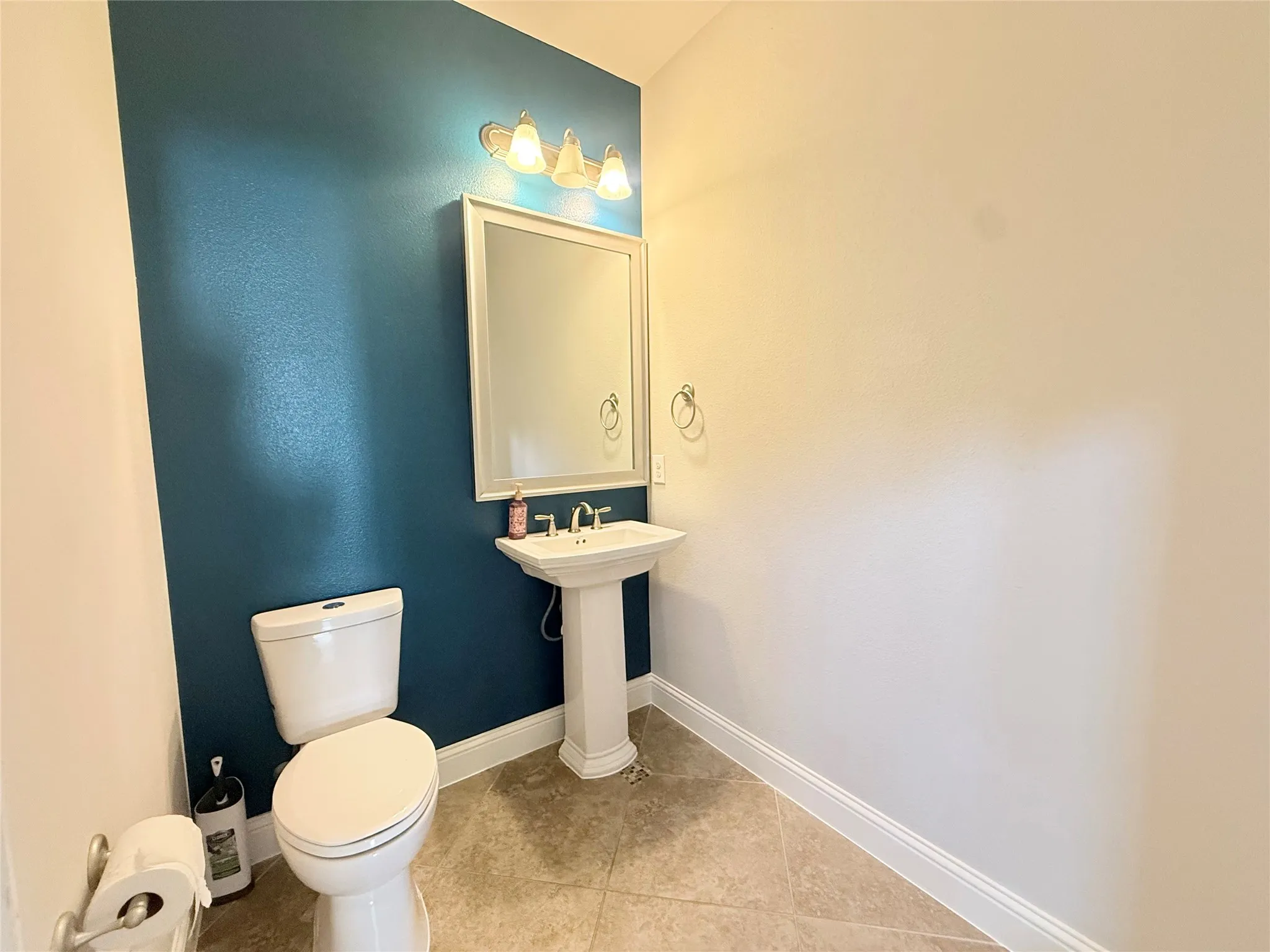 Pedestal sink with a framed mirror and wall-mounted vanity lighting