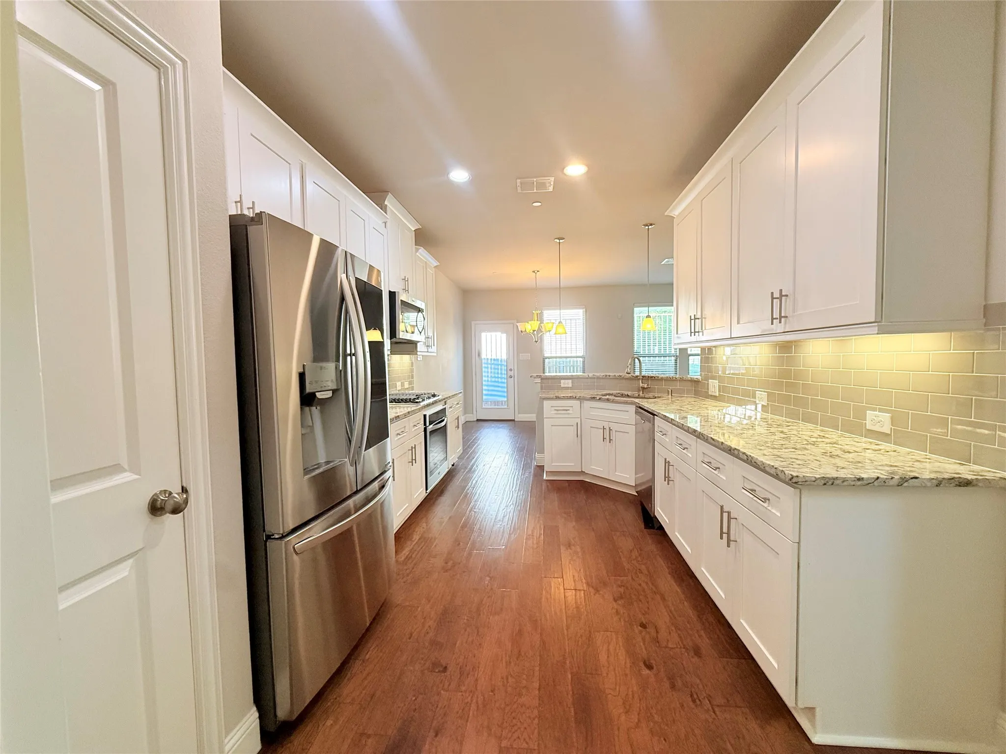Kitchen featuring wood-finish flooring, white cabinetry with brushed nickel hardware, and light-toned countertops