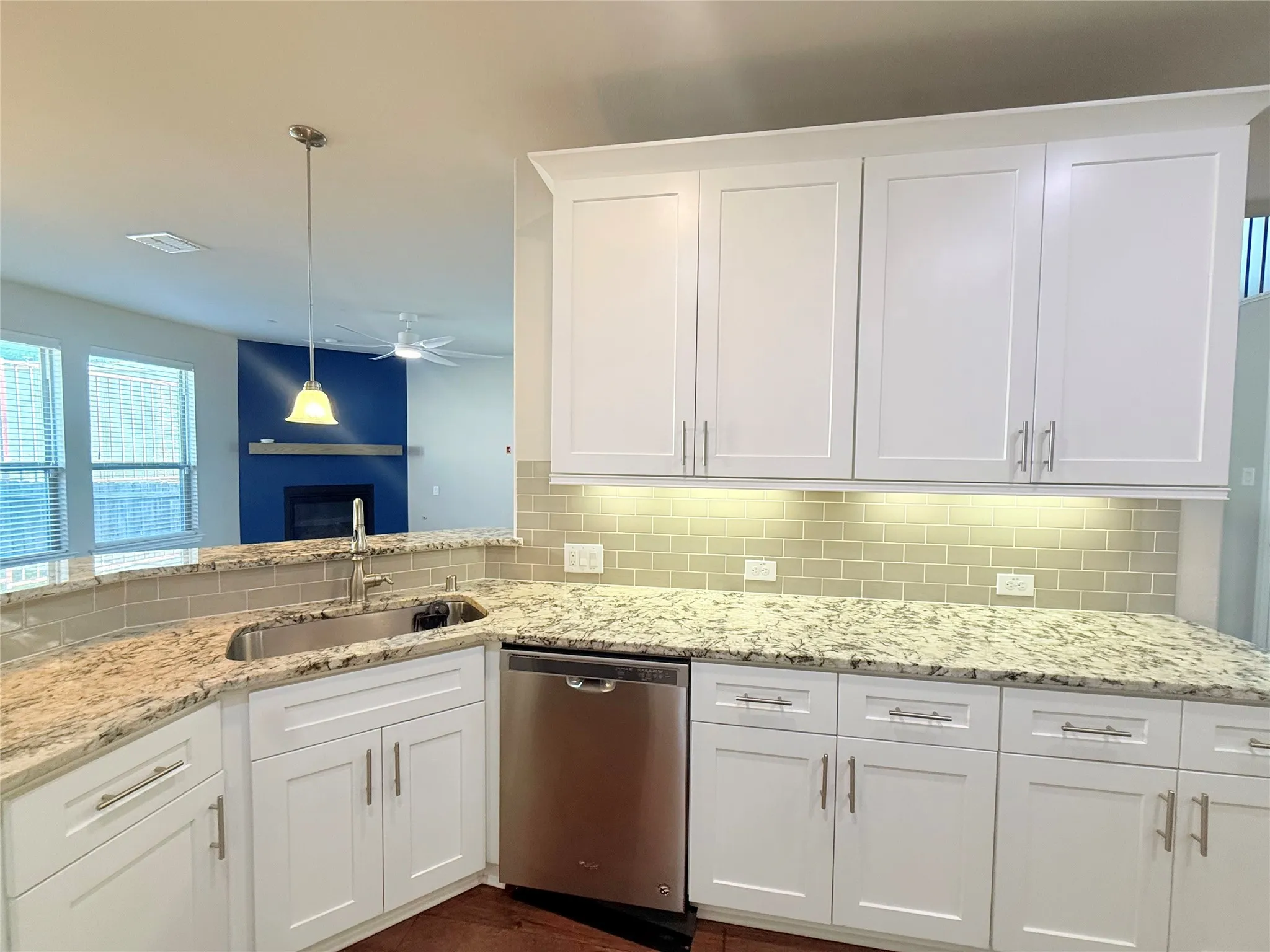Kitchen featuring white cabinetry, light-toned granite countertops, a stainless steel undermount sink, and a subway tile backsplash