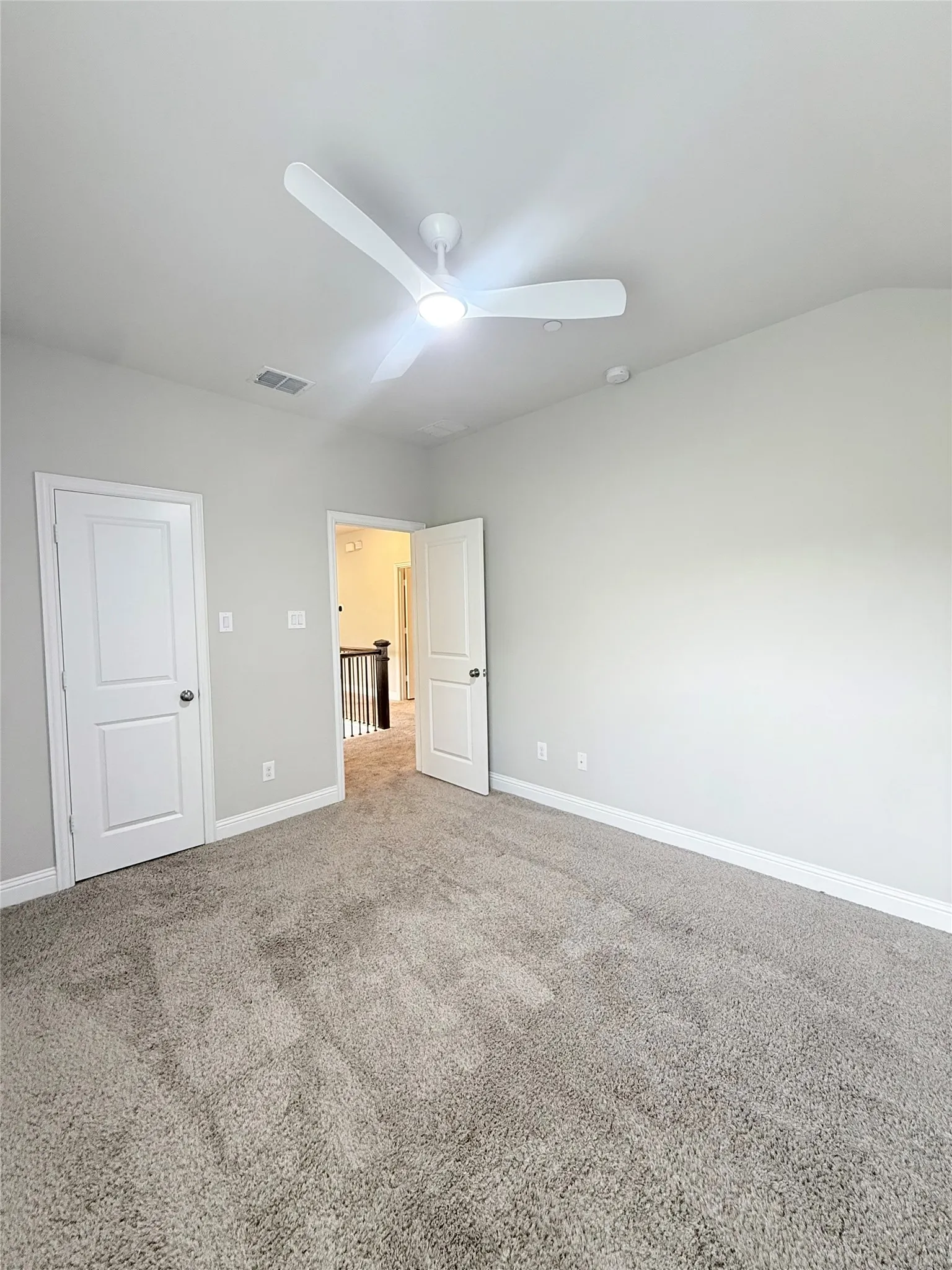 Carpeted room with a modern ceiling fan and light fixture