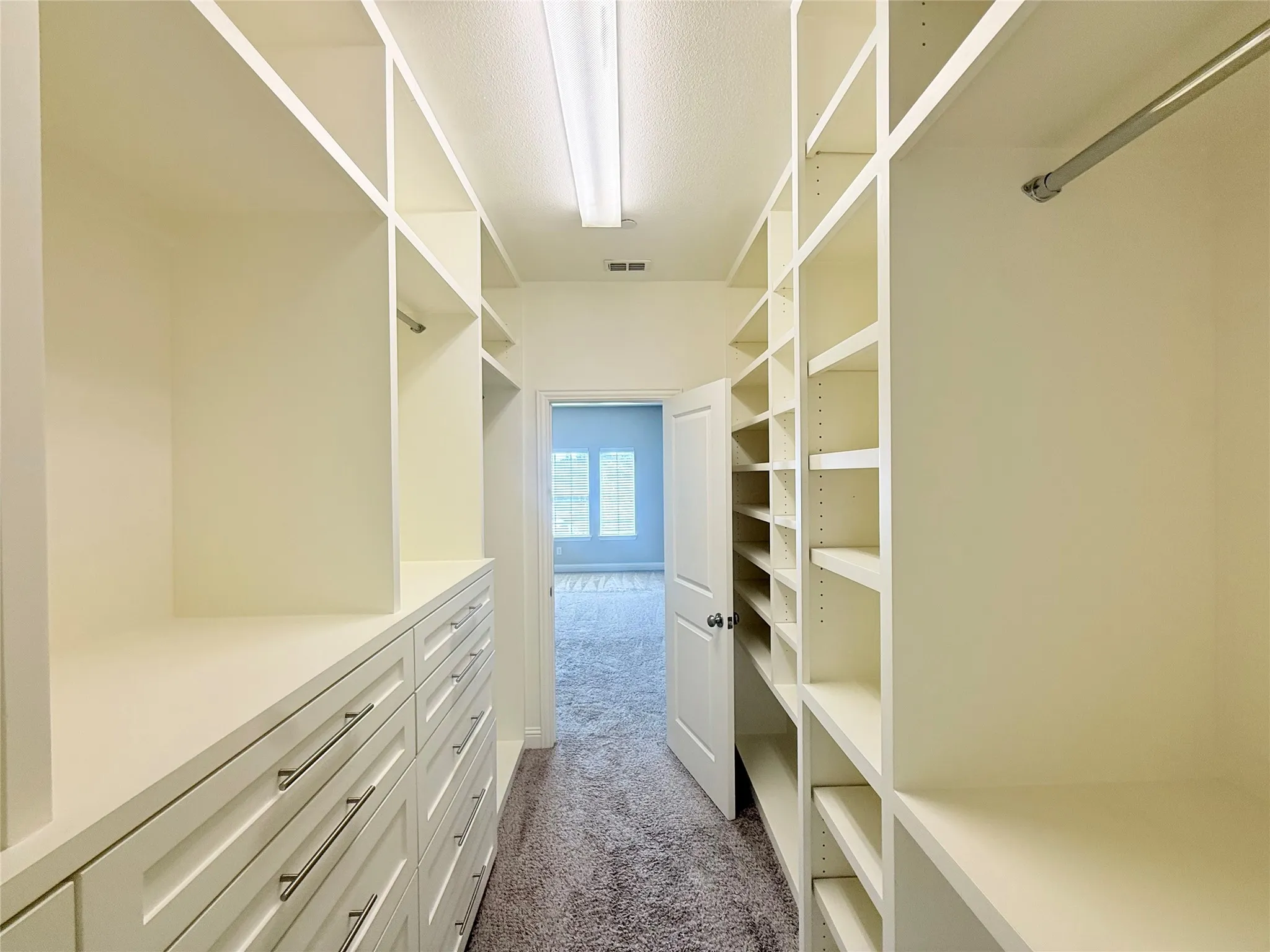 Custom closet system featuring extensive shelving, built-in drawer units with metal hardware, hanging rods, and recessed lighting