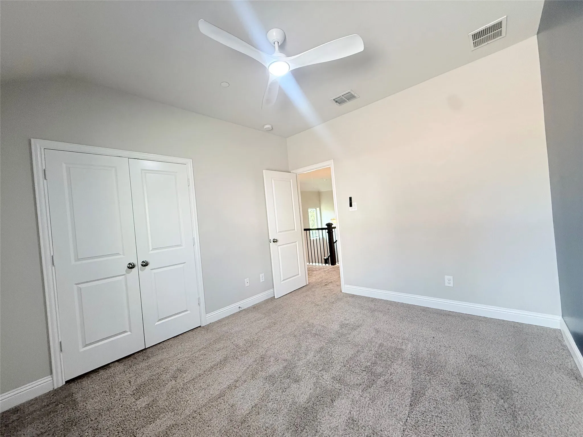 Carpeted room featuring a ceiling fan with integrated lighting, dual white bi-fold closet doors, and recessed lighting