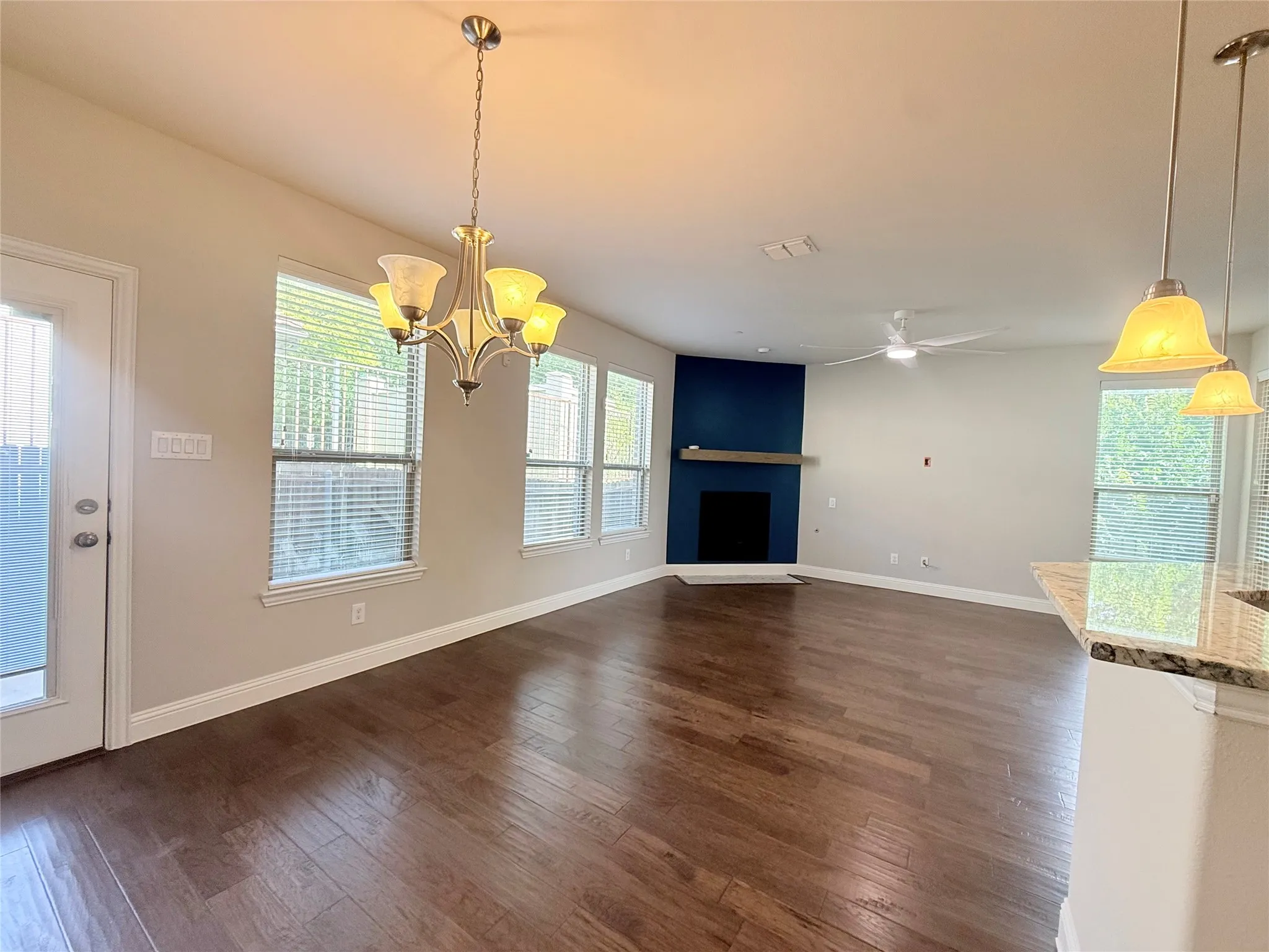 Open-concept living area featuring wood-finish flooring, a contemporary ceiling fan, and multiple windows