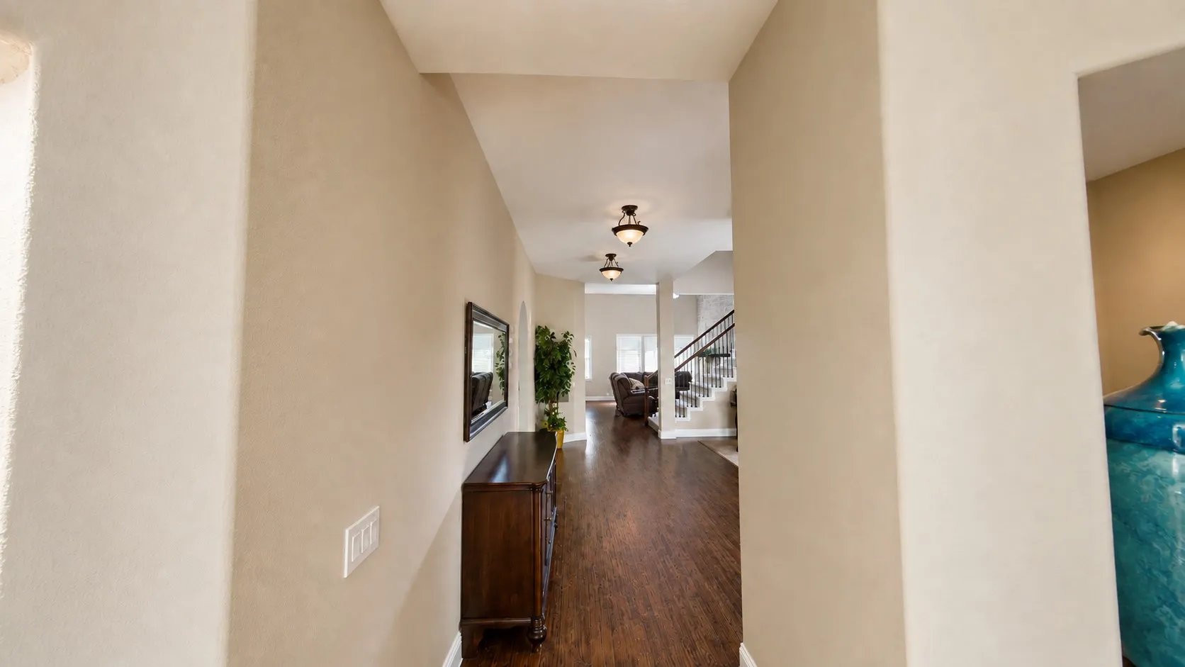 Hallway featuring wood-finish flooring, recessed lighting, and a staircase with dark railings