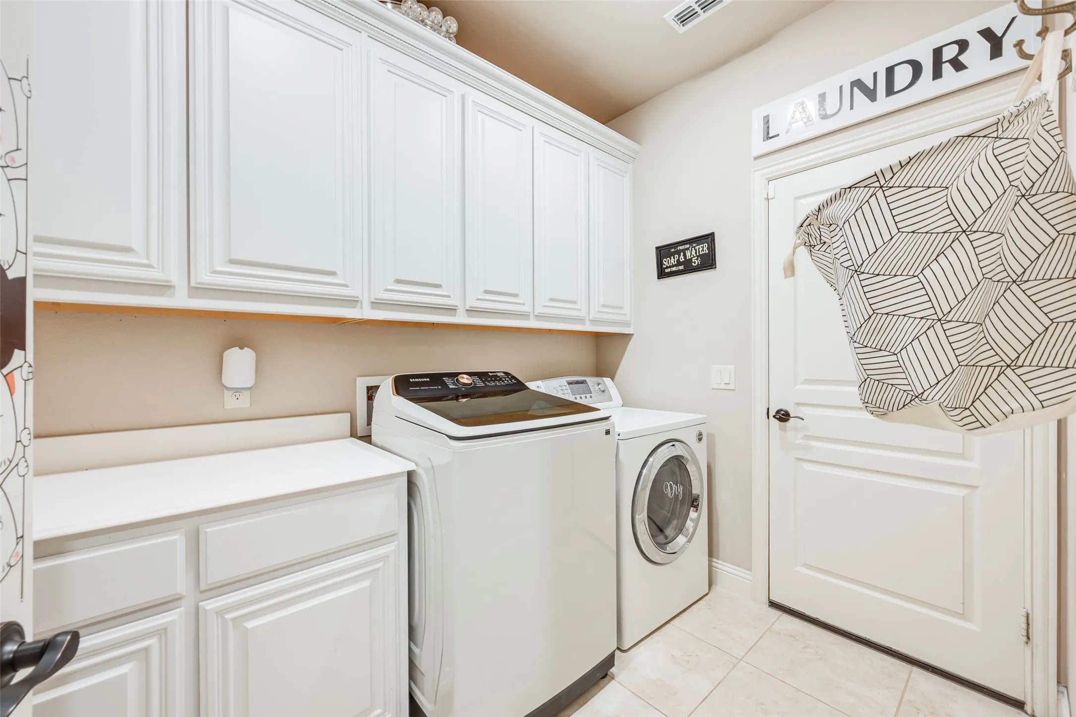 Built-in cabinetry with white shaker-style doors, ample counter space, and light-toned tile flooring