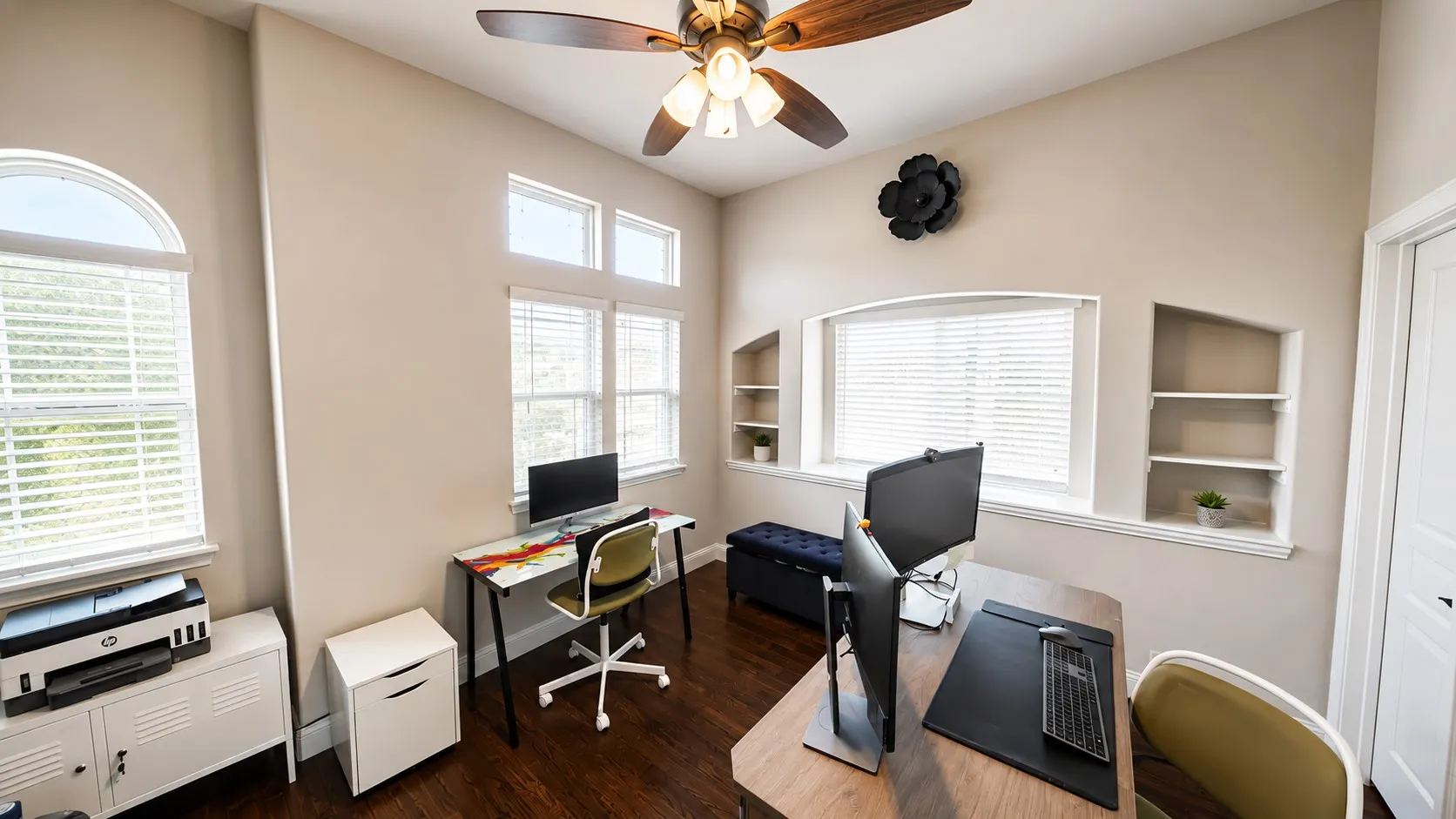 Vaulted ceiling, wood-finish flooring, ceiling fan, multiple windows with blinds, and built-in wall shelving