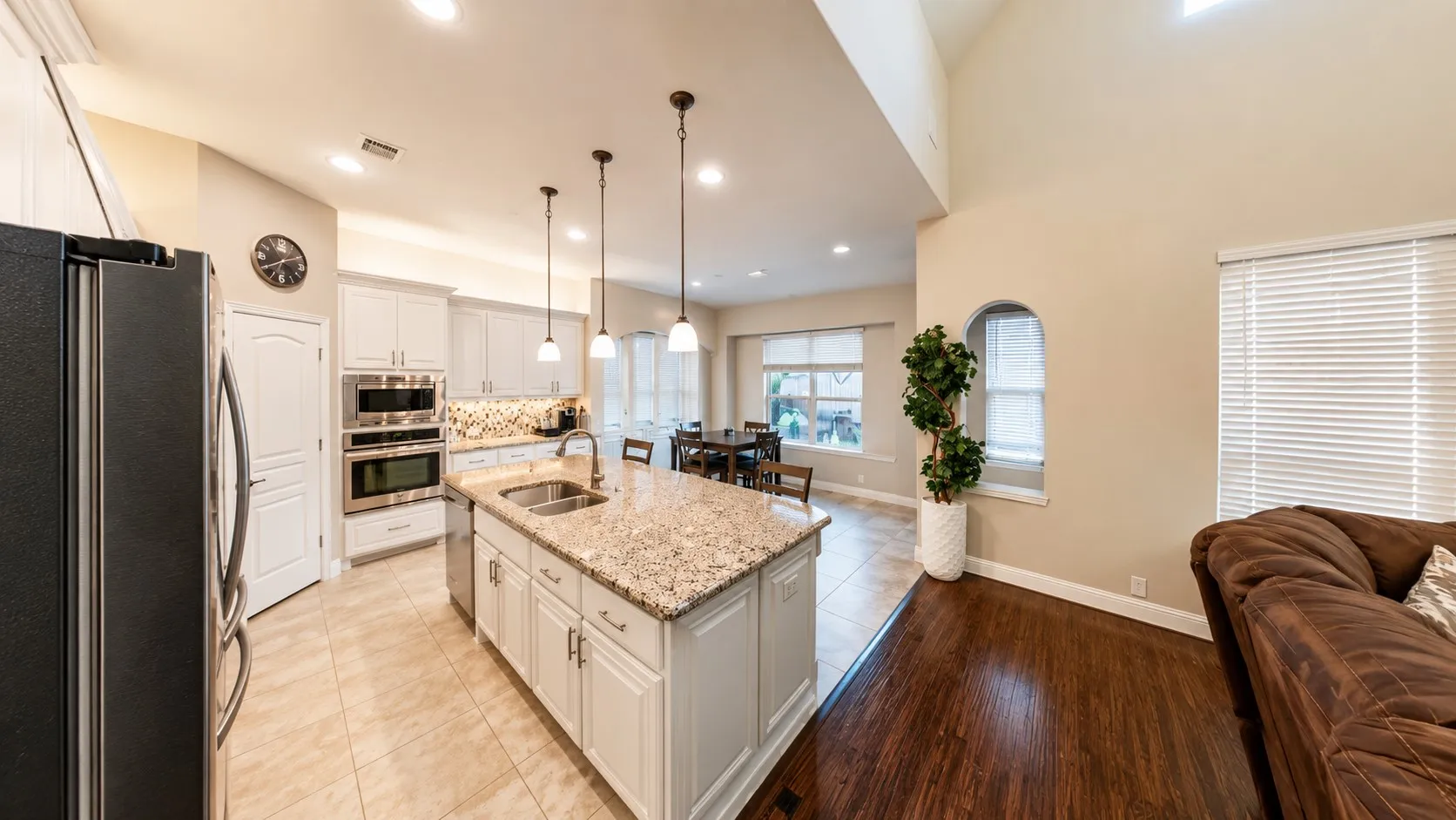 Kitchen with white cabinetry, stainless steel appliances, granite countertops, a center island with pendant lighting, and tile flooring