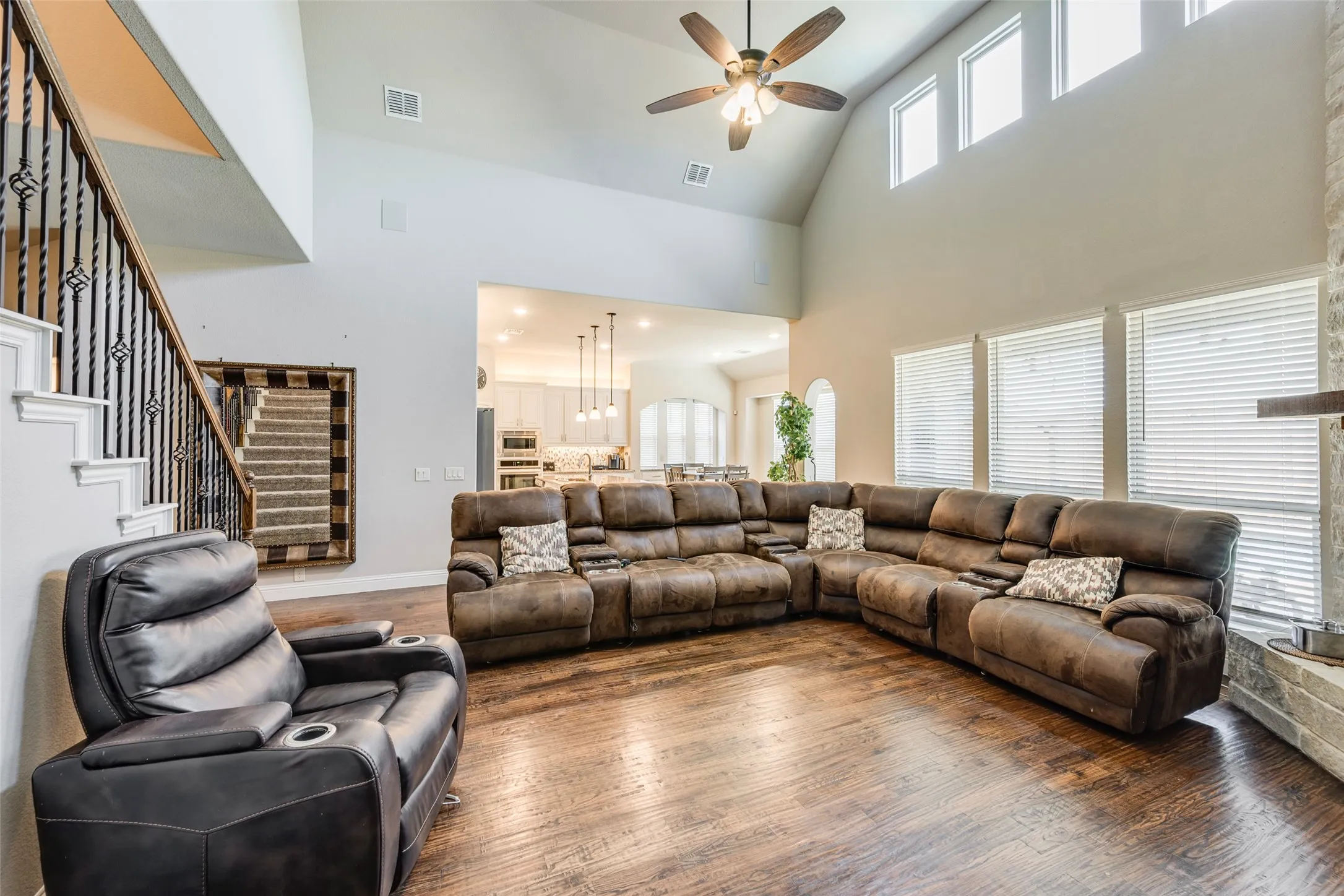 Wood-finish flooring, high vaulted ceiling, and a ceiling fan with integrated lighting