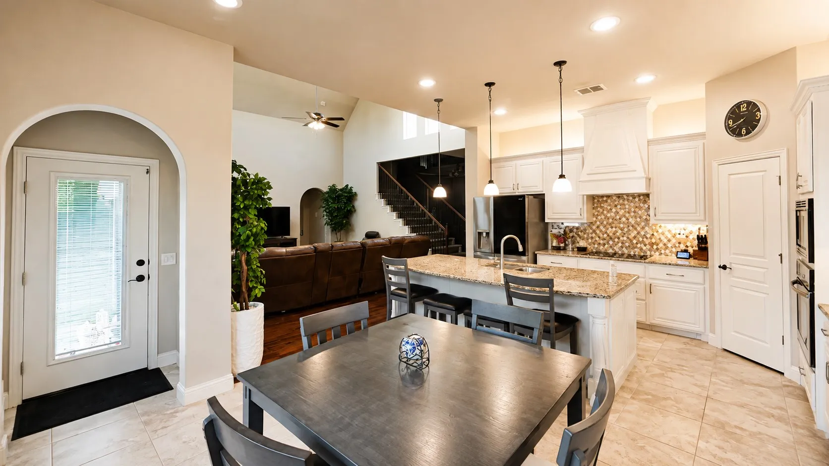Open-concept living space featuring a kitchen with a large island, stainless steel appliances, and a tiled backsplash
