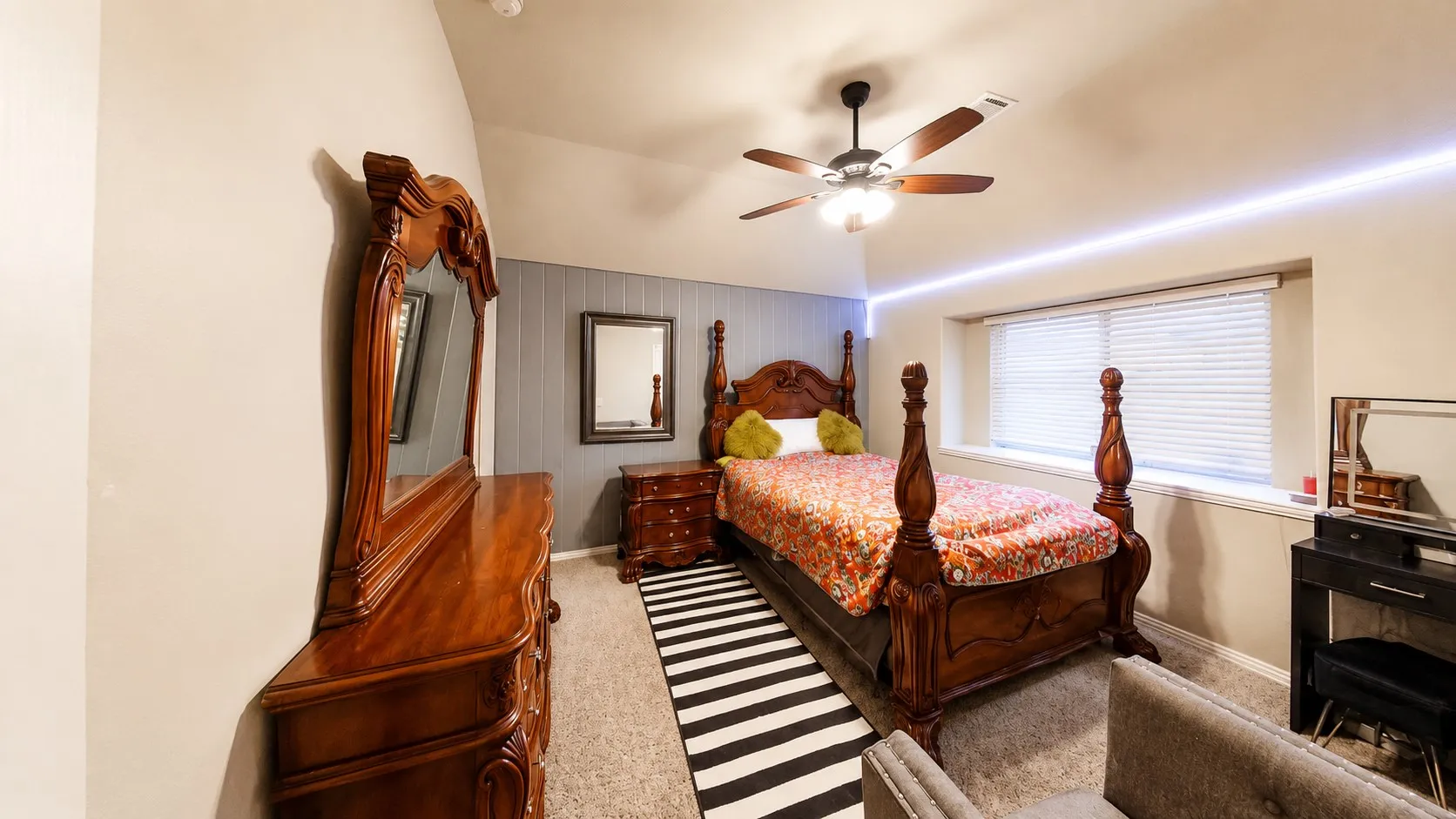 Recessed window with horizontal blinds, sloped ceiling, ceiling fan with integrated lighting, textured wall paneling, and wall-mounted strip lighting