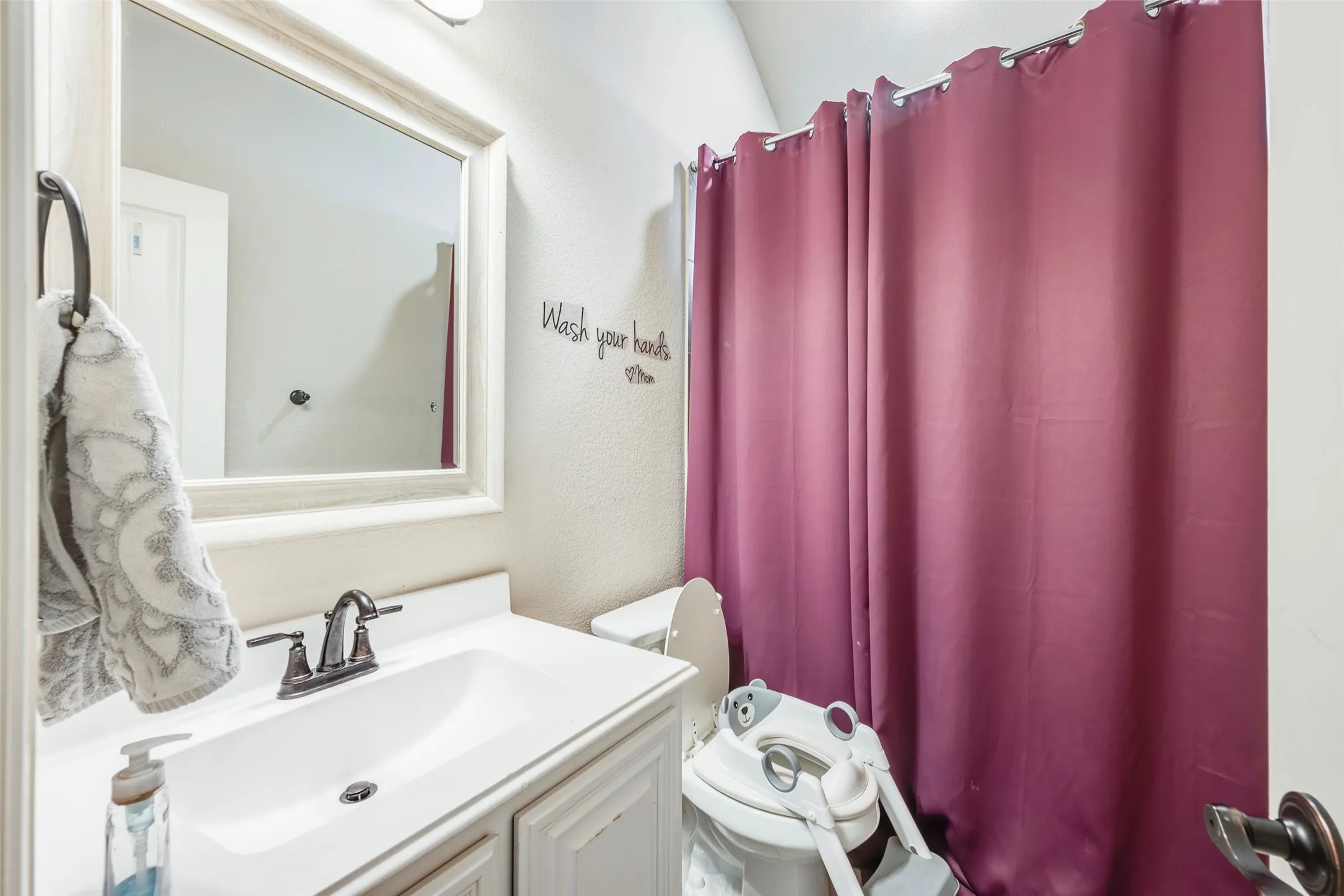 Vanity with an integrated sink, framed mirror, and a wall-mounted light fixture
