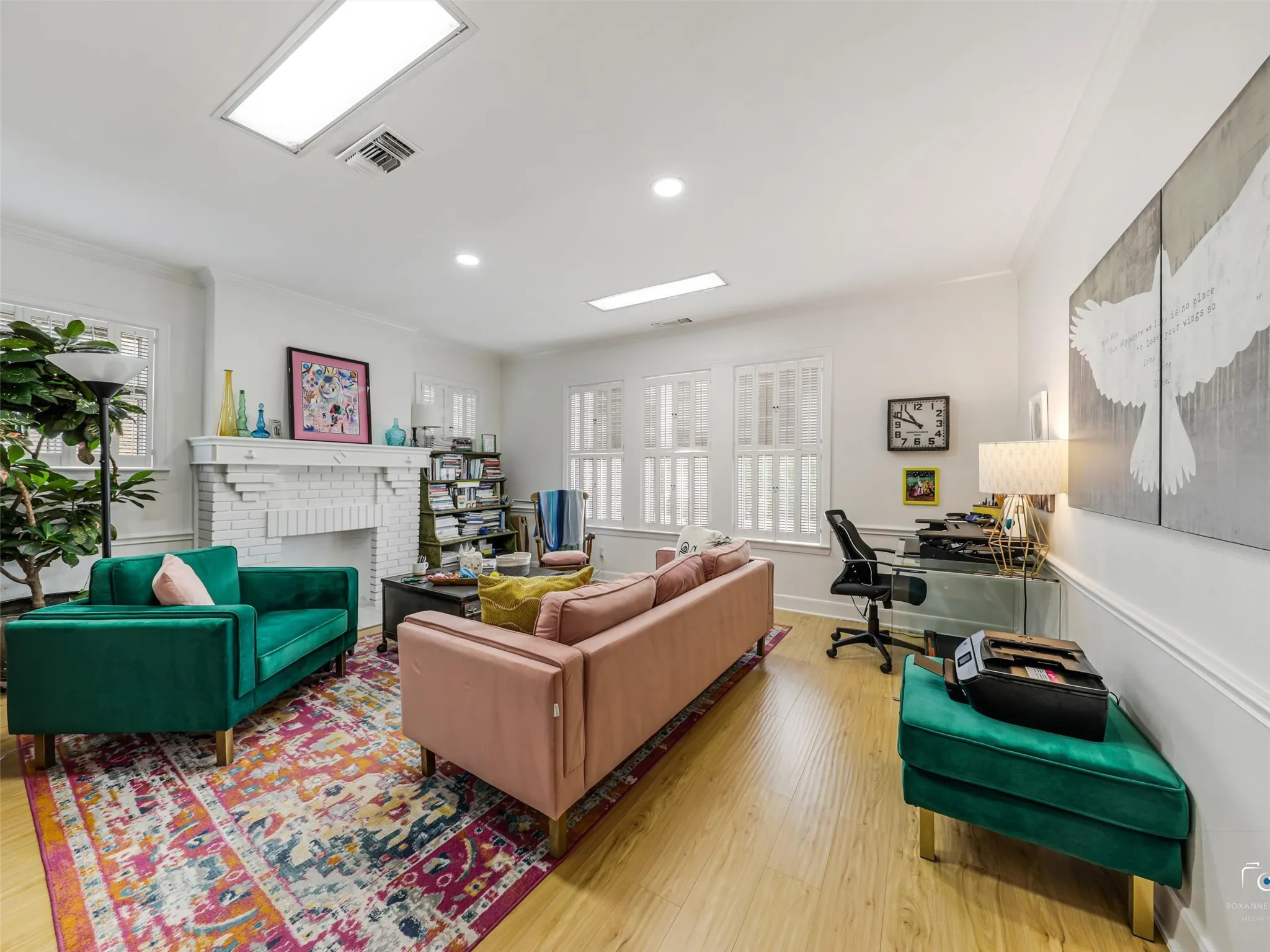 Second floor office with walls of shuttered windows and white brick fireplace.