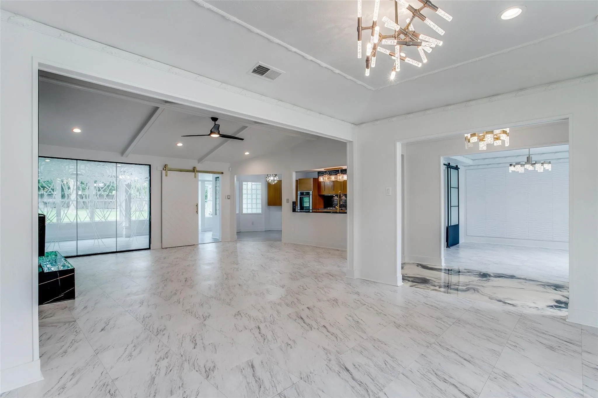 Spacious living area featuring polished marble-finish flooring and a contemporary chandelier