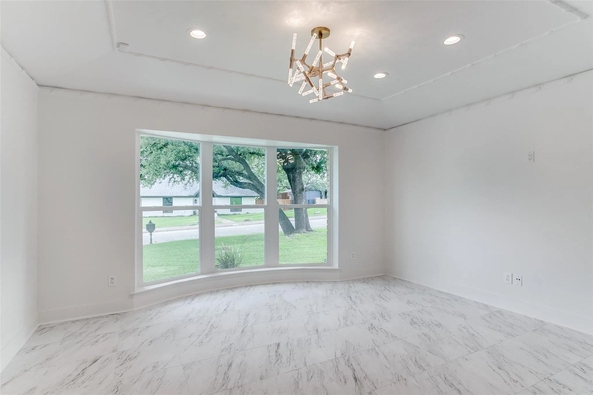 Bay window with white trim, marble-look tile flooring, tray ceiling, recessed lighting, and a contemporary brass light fixture