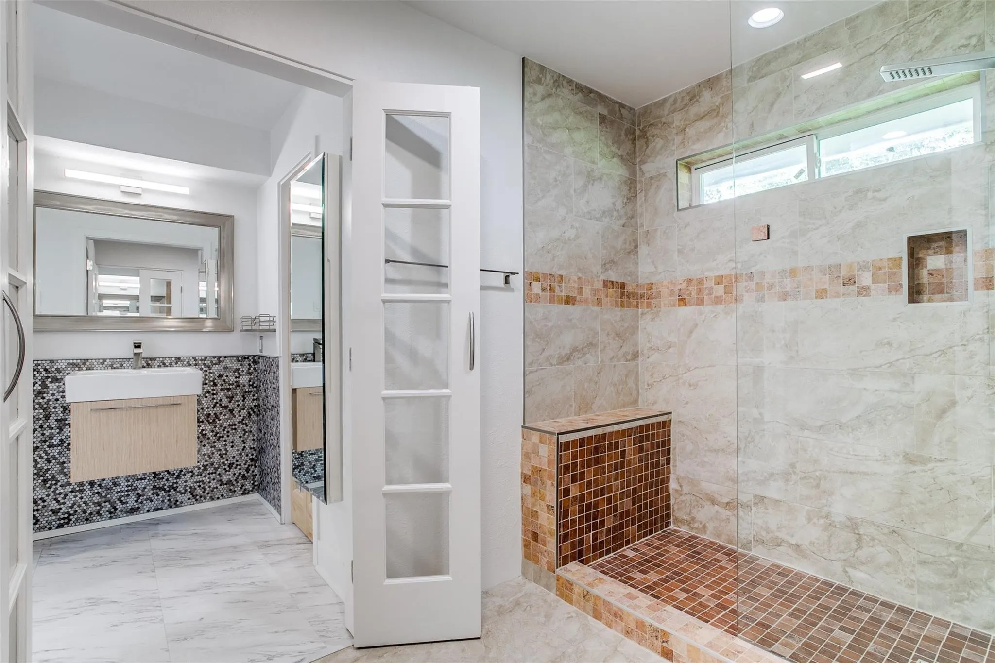 Tiled shower enclosure featuring a built-in bench, integrated niche, and transom window