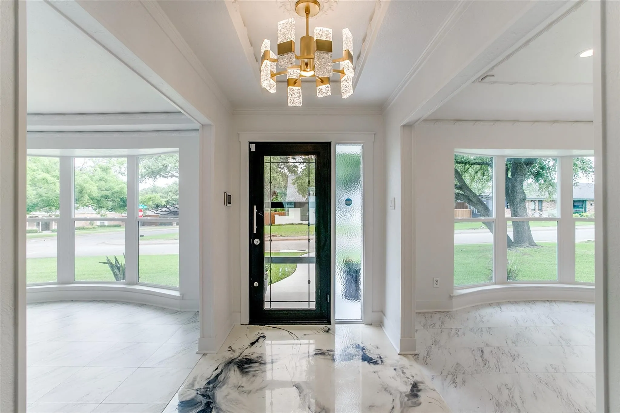 Foyer featuring a modern chandelier, a black framed entry door with a frosted sidelight, and marble-look flooring