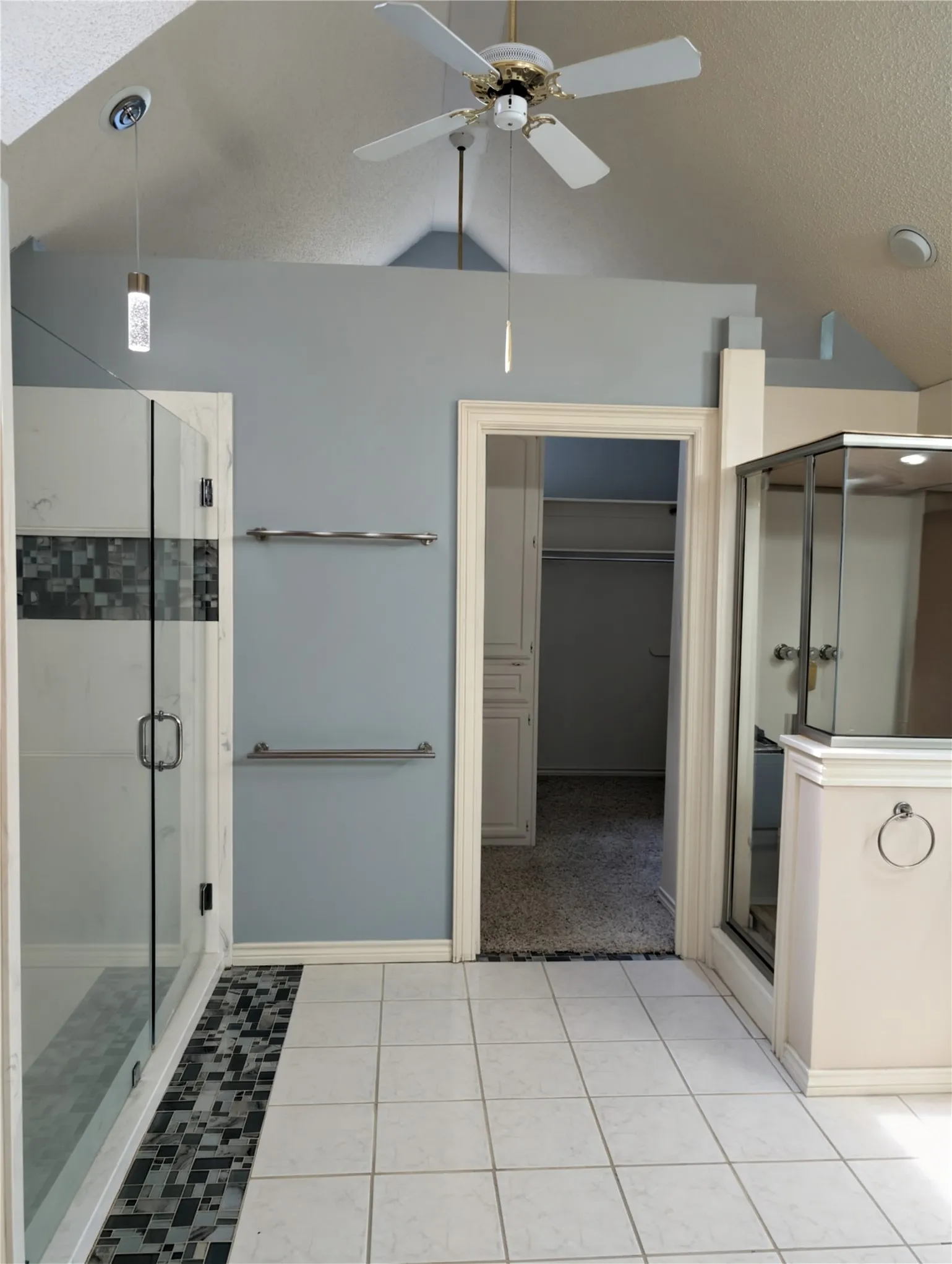 Bathroom featuring a glass-enclosed shower with mosaic tile accents, white square floor tiles, dry sauna, and a vaulted ceiling with a ceiling fan