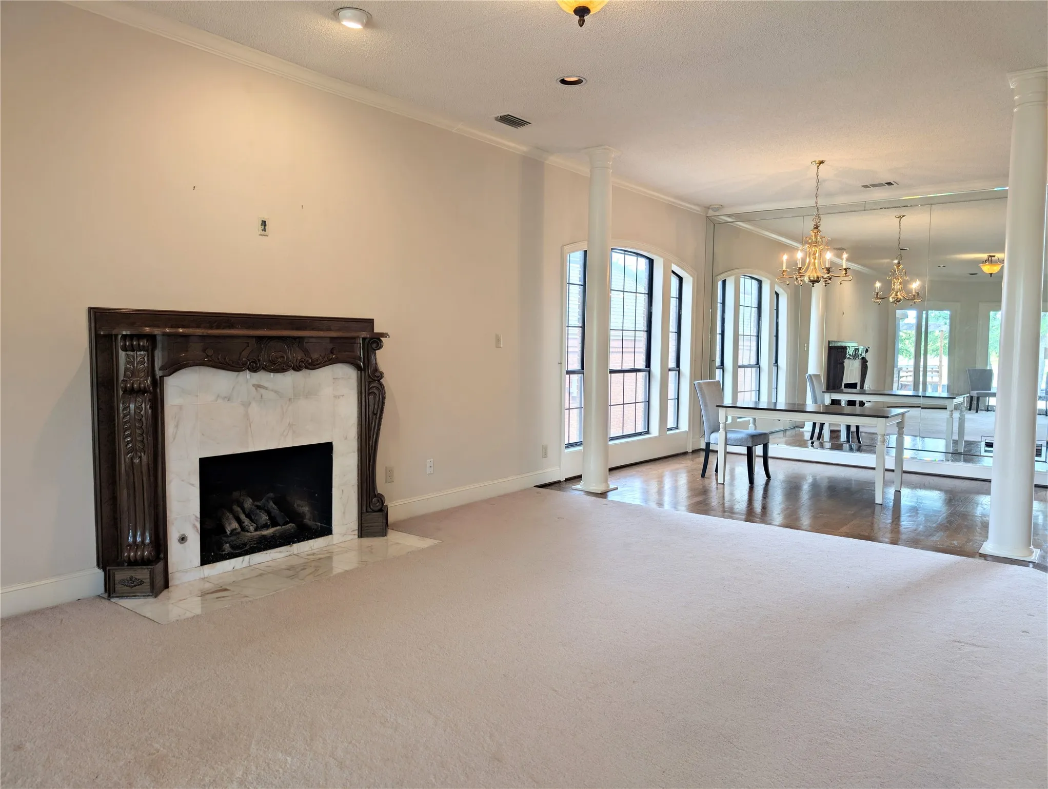 Spacious formal living area featuring a decorative fireplace with a carved wood surround and marble-style hearth
