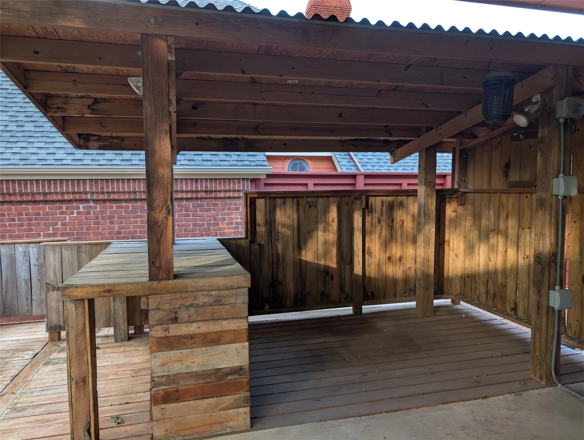 Outdoor patio featuring a built-in bar, wood-plank flooring, wood-paneled walls, and a corrugated roof