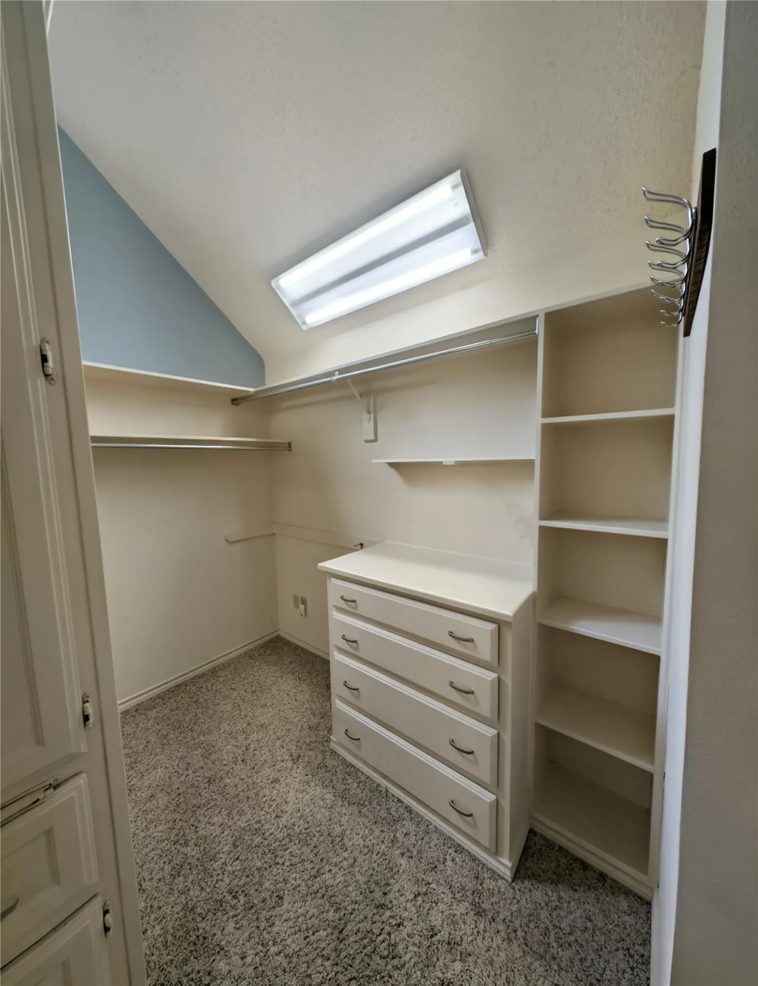 Walk-in closet featuring built-in shelving, hanging rods, an integrated four-drawer dresser, and a multi-hook rack