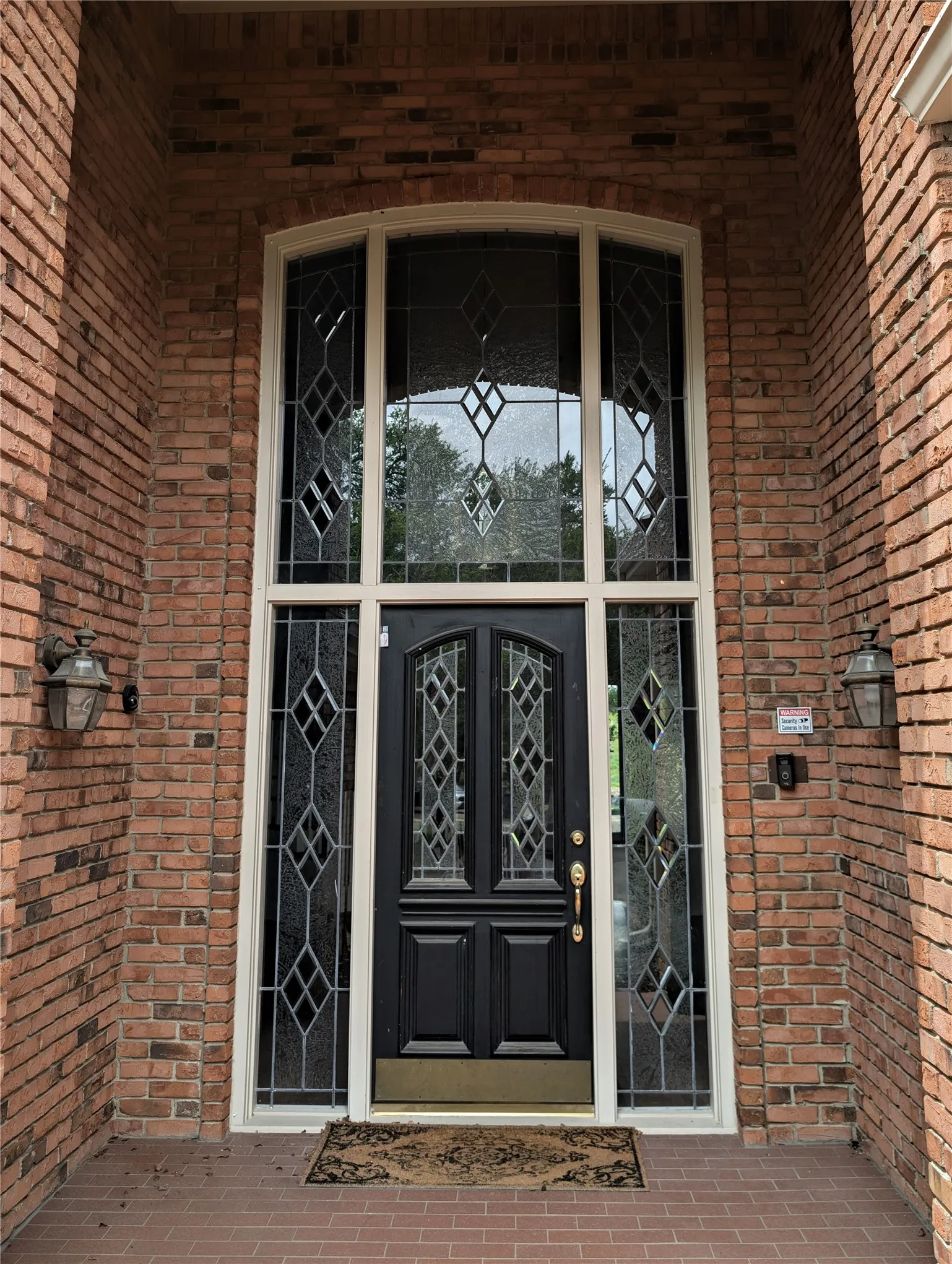 Brick exterior featuring a grand arched entryway with an ornate double door and leaded glass sidelights