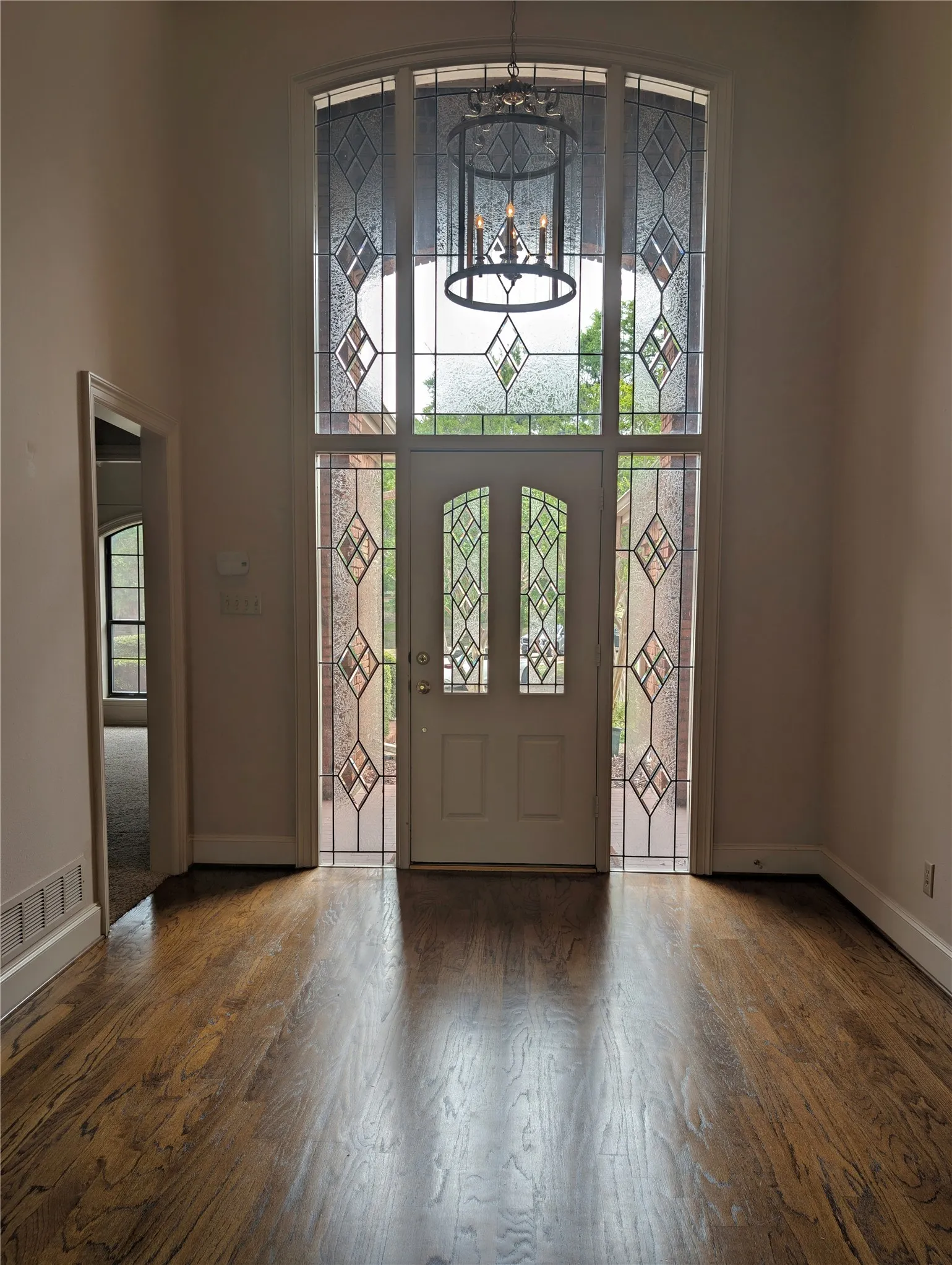 Grand entryway featuring a double door with decorative glass inserts, flanked by matching sidelights and an arched transom window above
