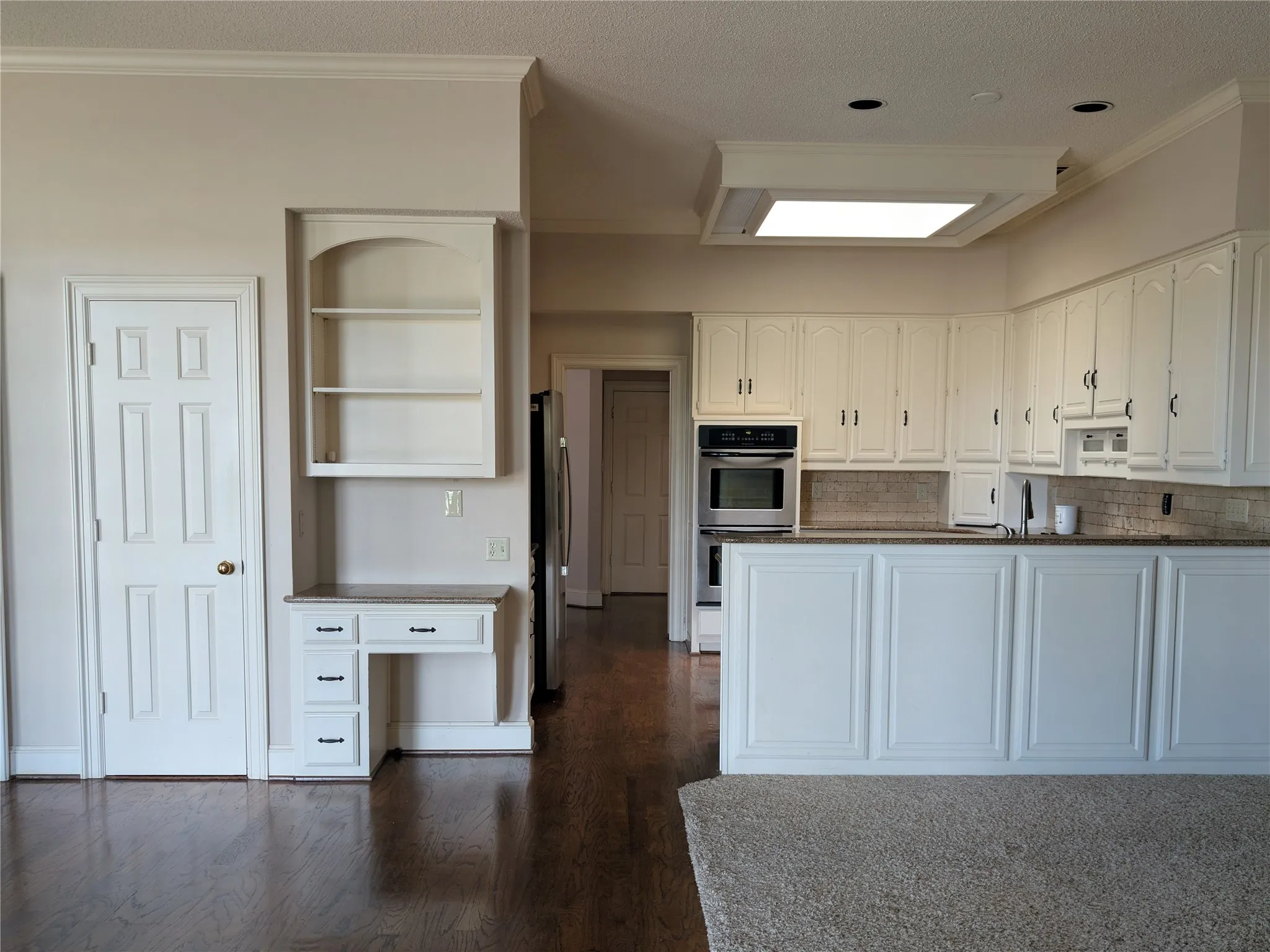 Kitchen featuring white cabinetry, stone countertops, a tile backsplash, and stainless steel built-in appliances