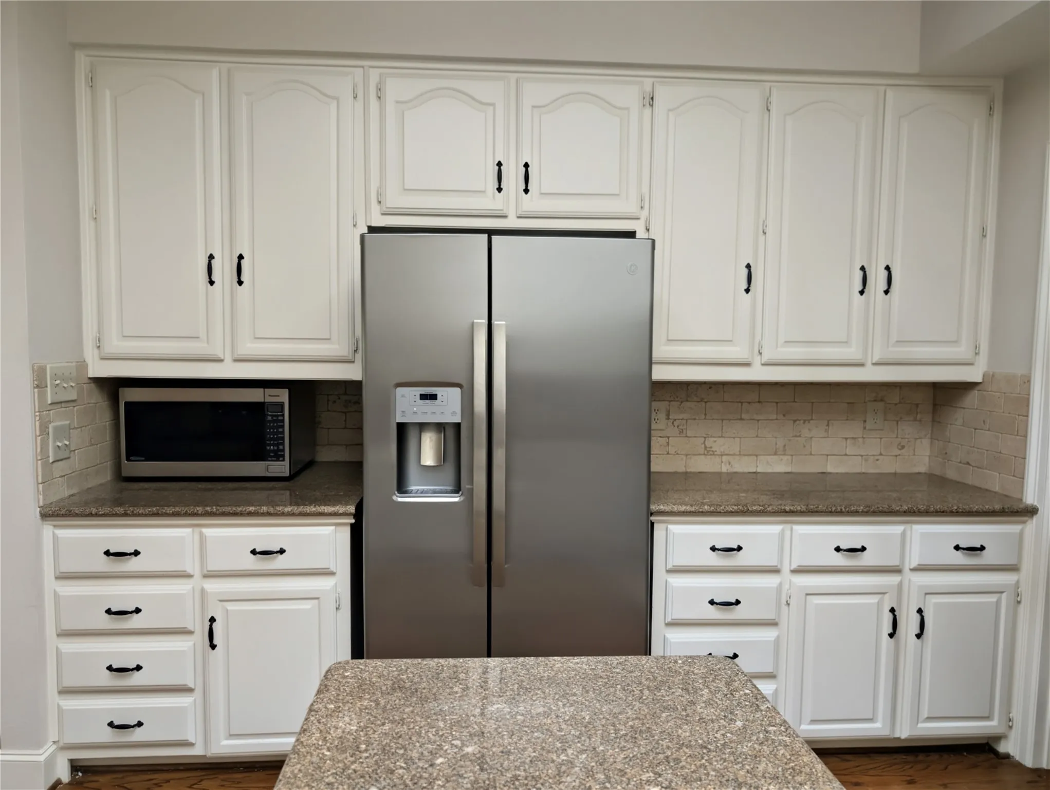 Kitchen featuring white cabinetry, a stainless steel side-by-side refrigerator, granite countertops, and a subway tile backsplash