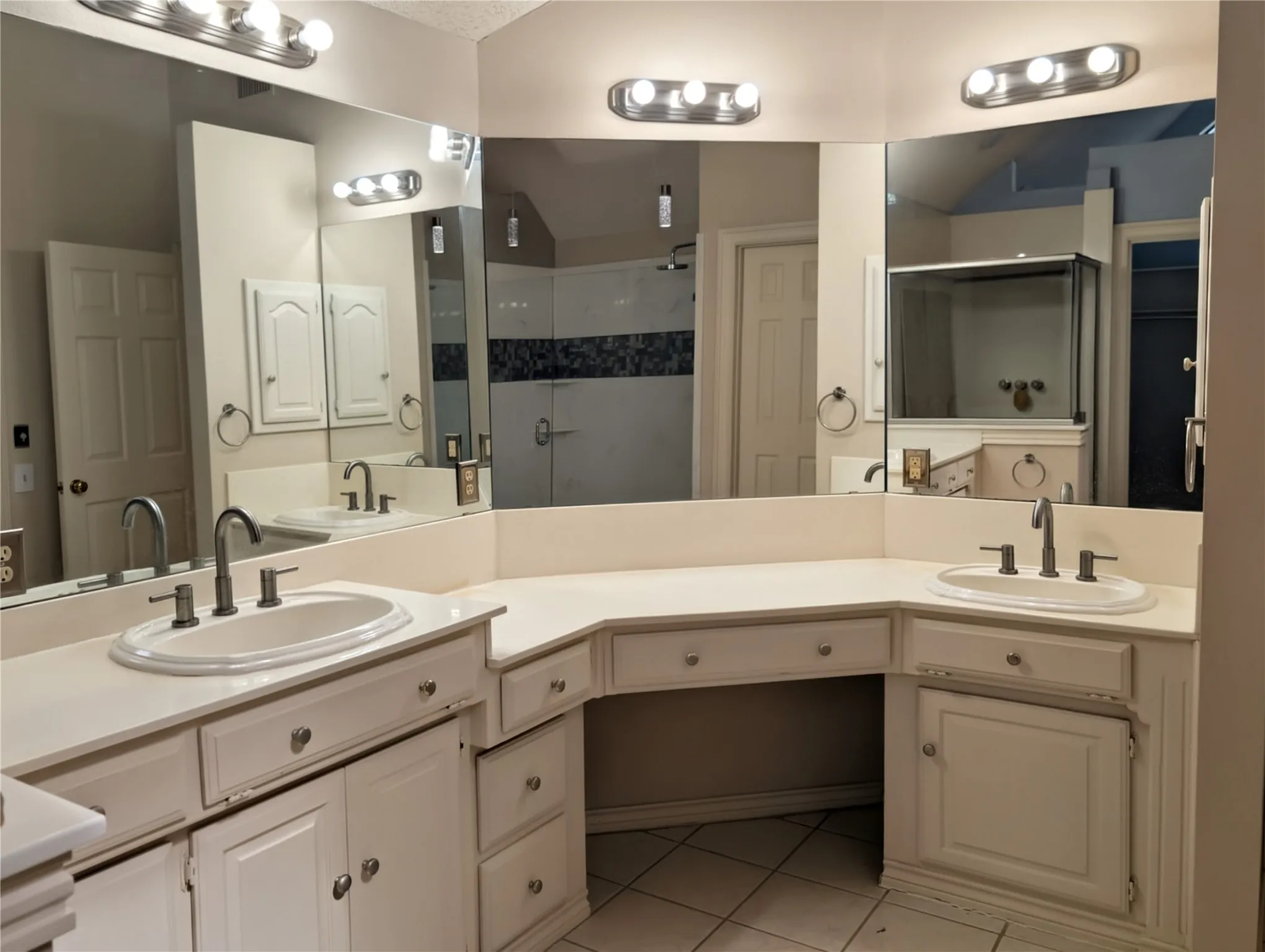 Bathroom vanity featuring dual sinks, an integrated makeup area, extensive counter space, and white cabinetry with silver-tone hardware