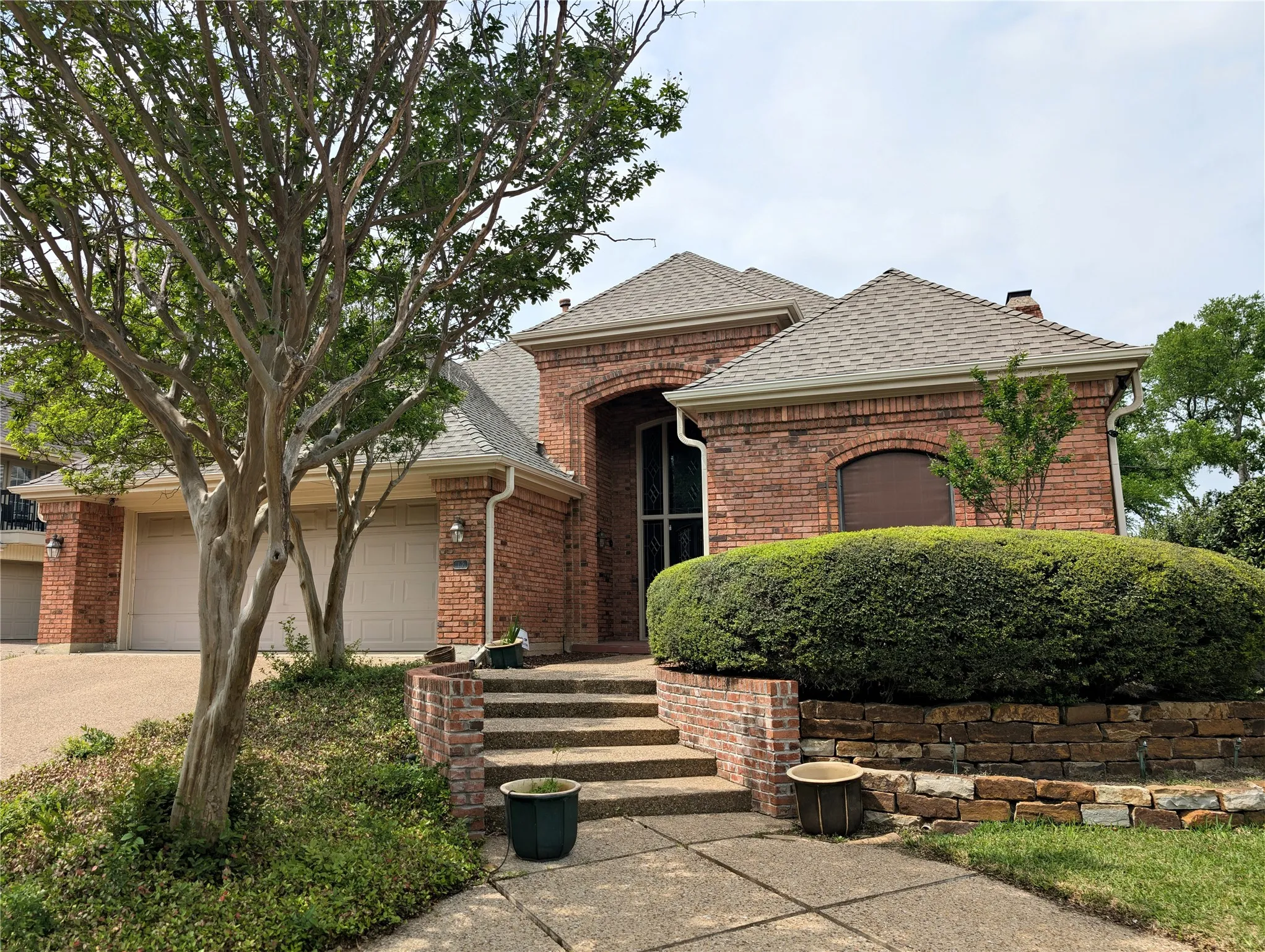 Brick exterior featuring a multi-car garage with individual doors, a prominent arched entry, and a gabled roofline