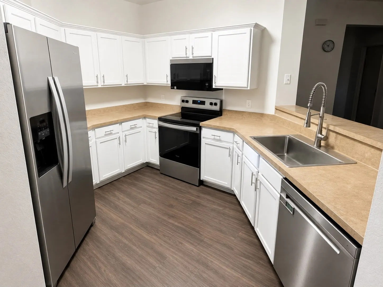 Kitchen featuring white cabinetry, wood-finish flooring, stainless steel appliances, a double basin sink, and a contrasting countertop
