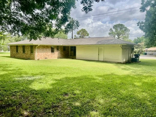 Expansive rear lawn featuring a brick exterior and horizontal siding