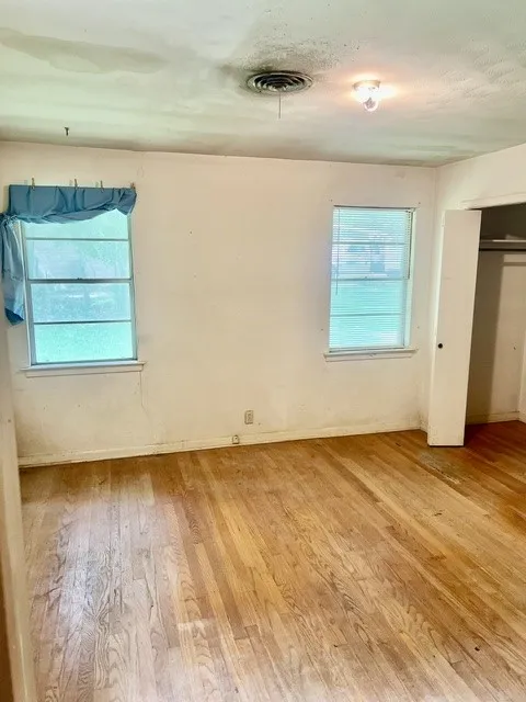 Hardwood flooring spans this room, featuring two windows with horizontal blinds