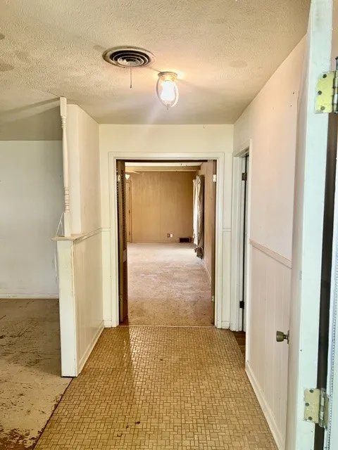 Hallway featuring mosaic tile flooring and white wainscoting