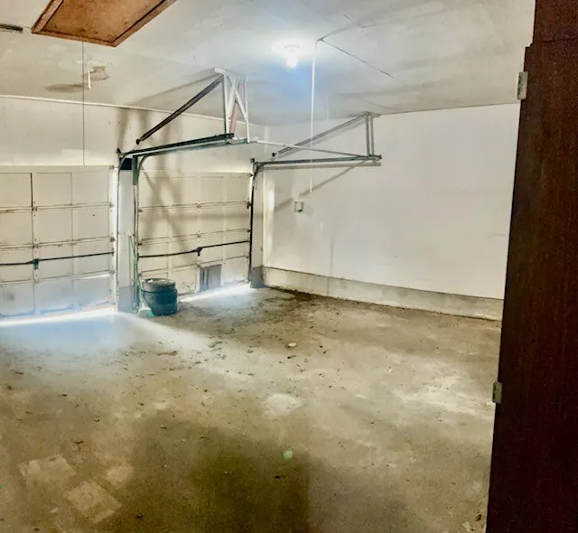 Spacious garage featuring two overhead doors, a concrete floor, and white painted walls